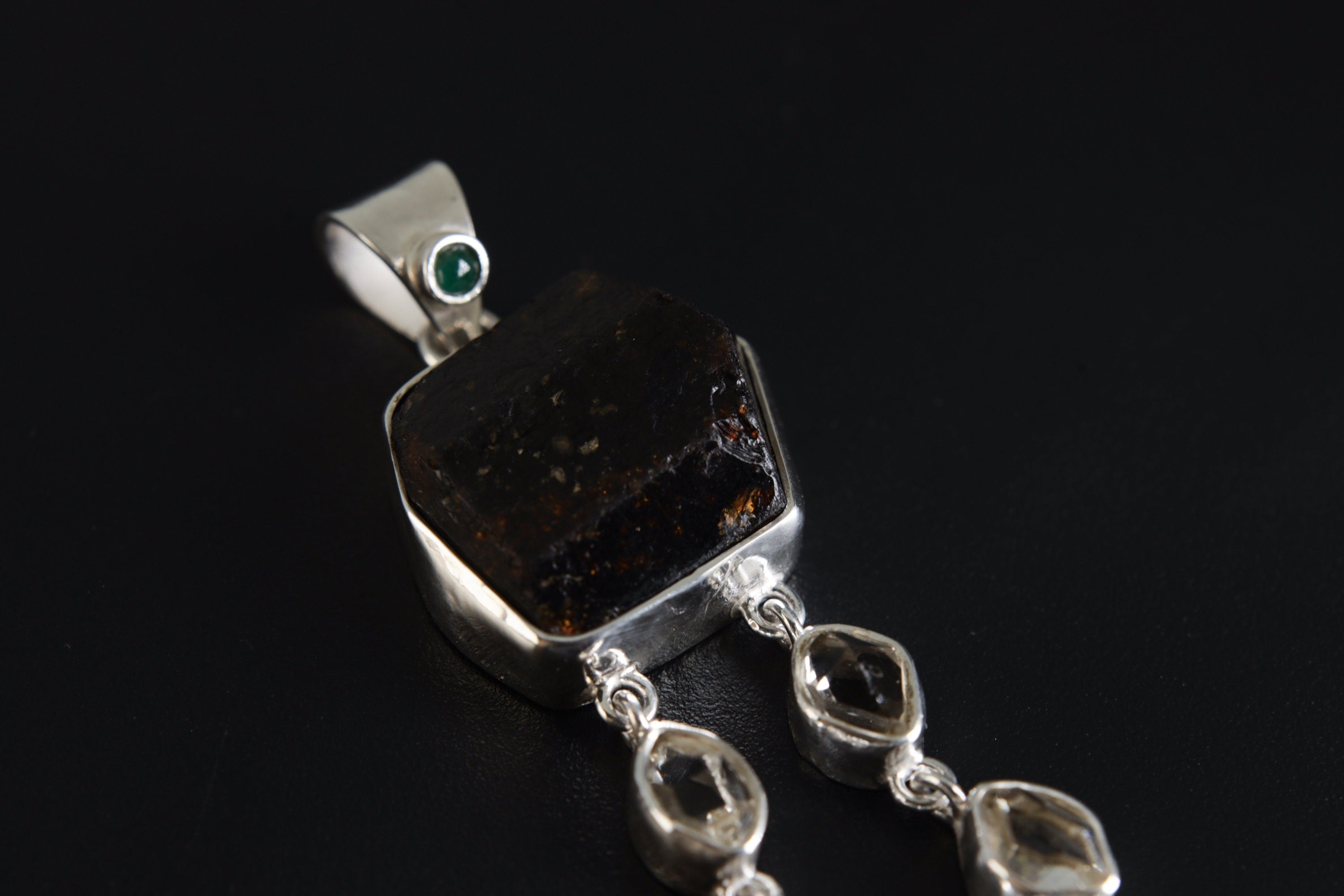 Close-up of round Emerald accent and Dravite Tourmaline in a hammered polished sterling silver statement pendant.