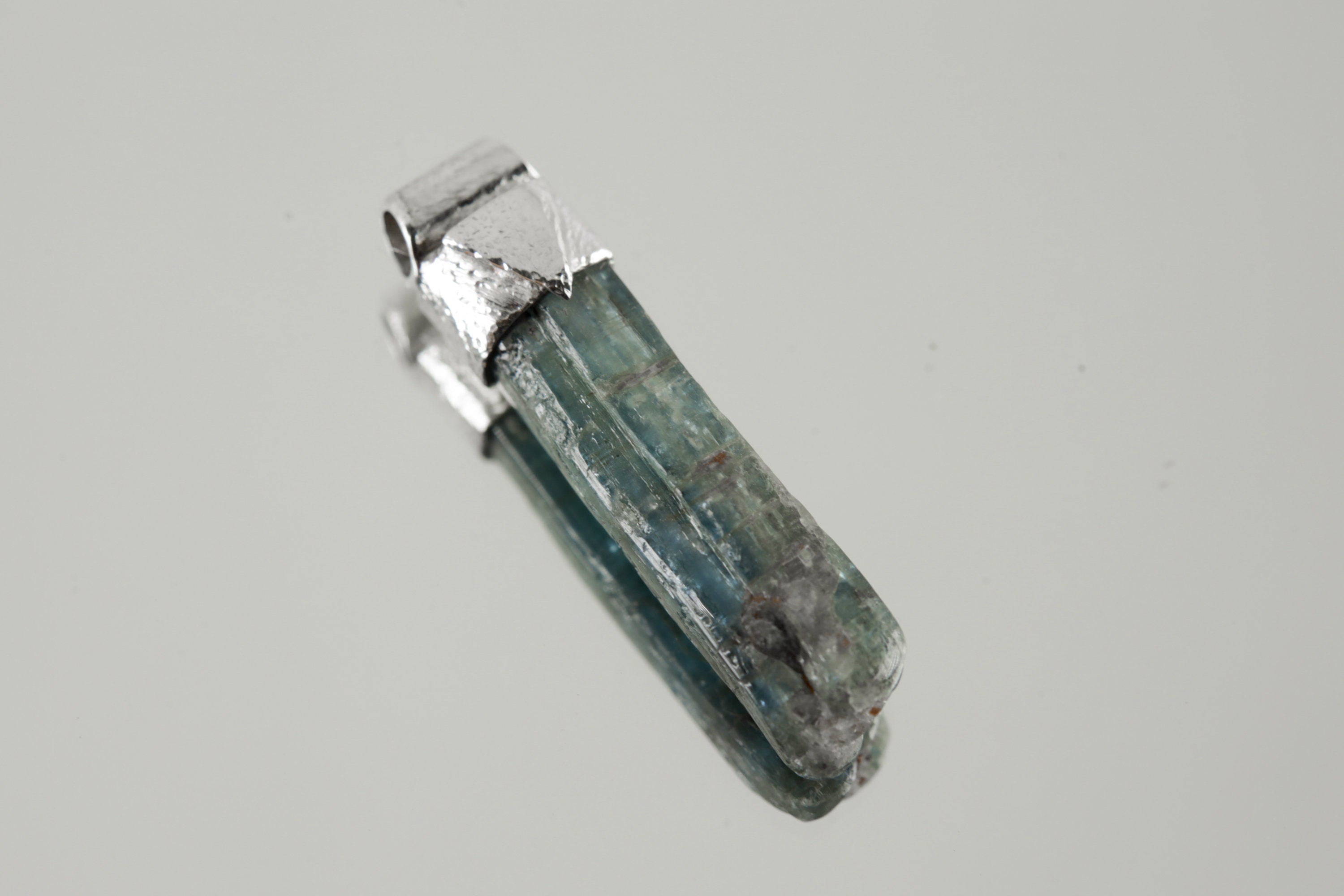 Kyanite Stack Pendant shown worn on the chest with sterling silver cap and blue bladed crystal.