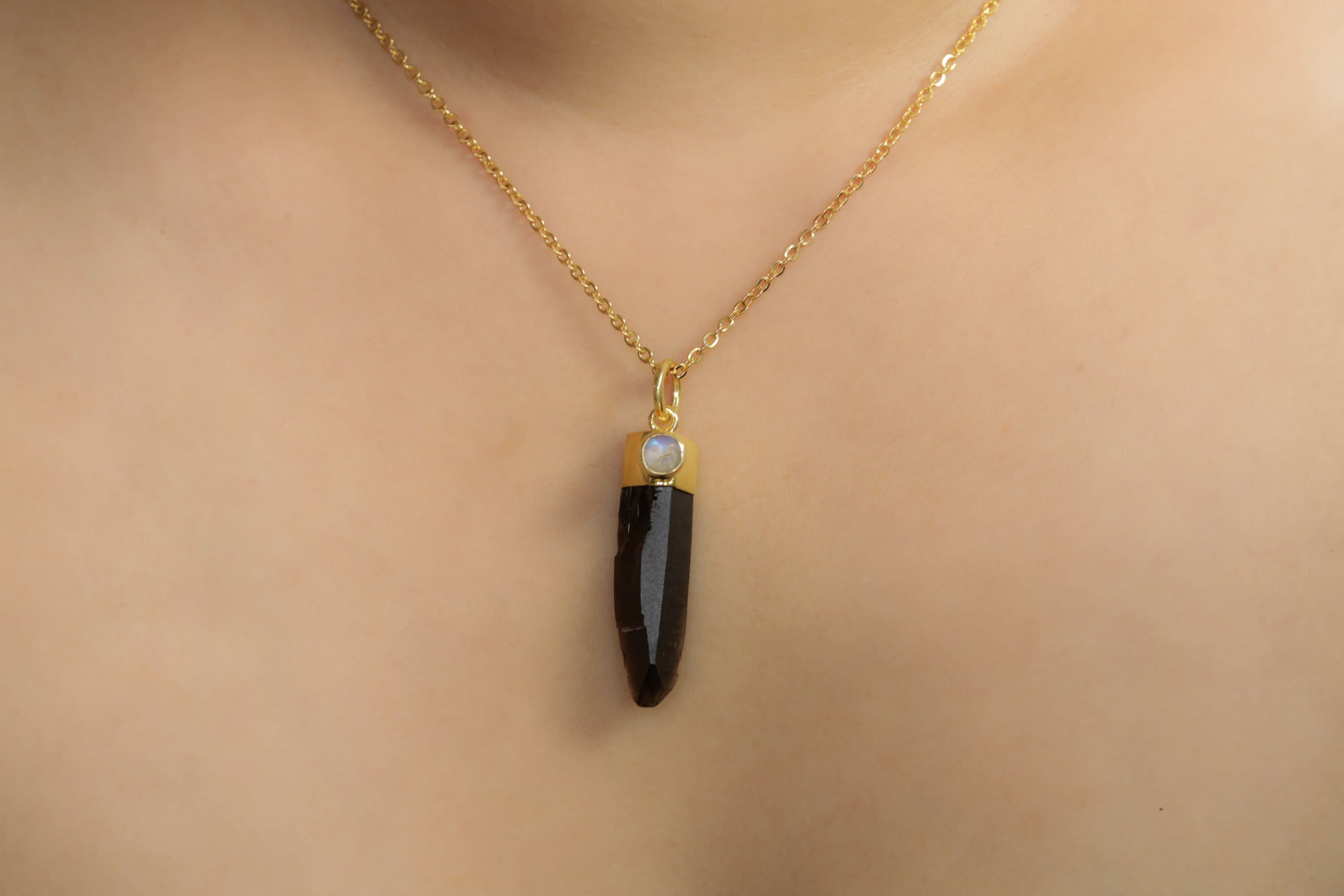 Smoky Phantom Quartz Blue Moonstone pendant worn on a model with gold chain and oval lunar cabochon detail.