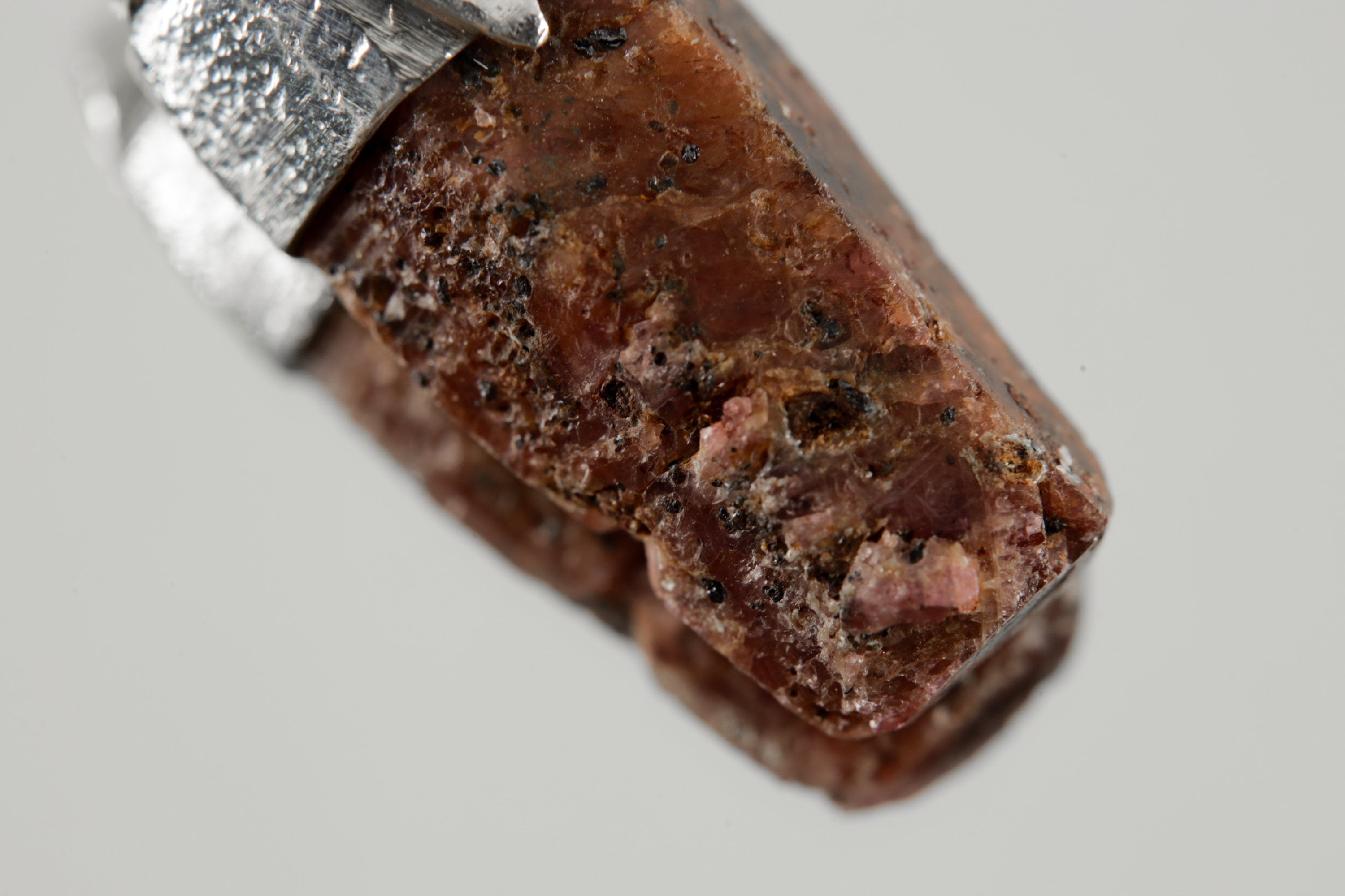 Close-up of Hexagonal Ruby showing natural red corundum texture, earthy surface detail, and organic sterling silver cap.