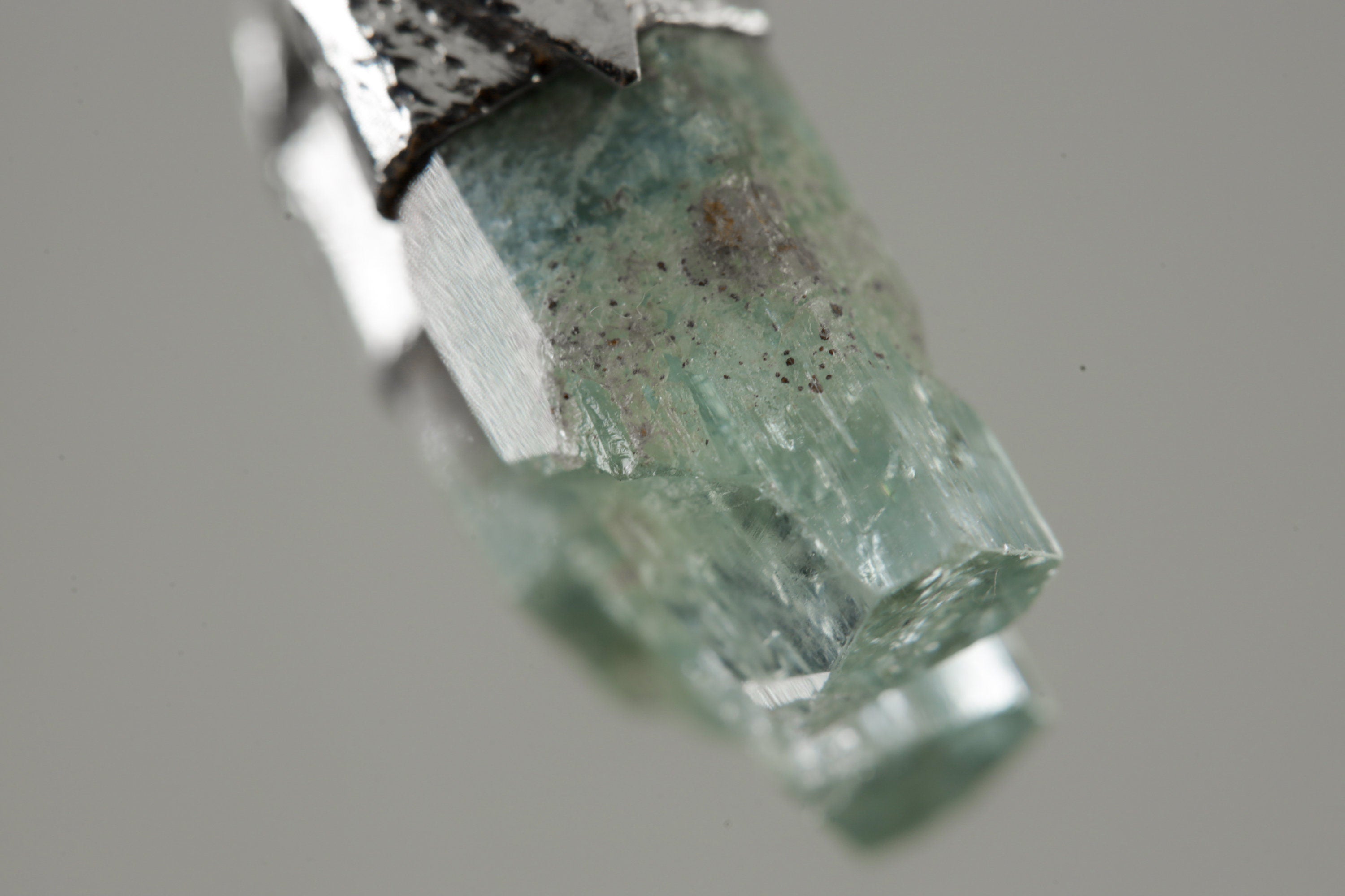 Close-up of Aquamarine showing soft blue-green colour, natural mineral texture, and organic silver cap.