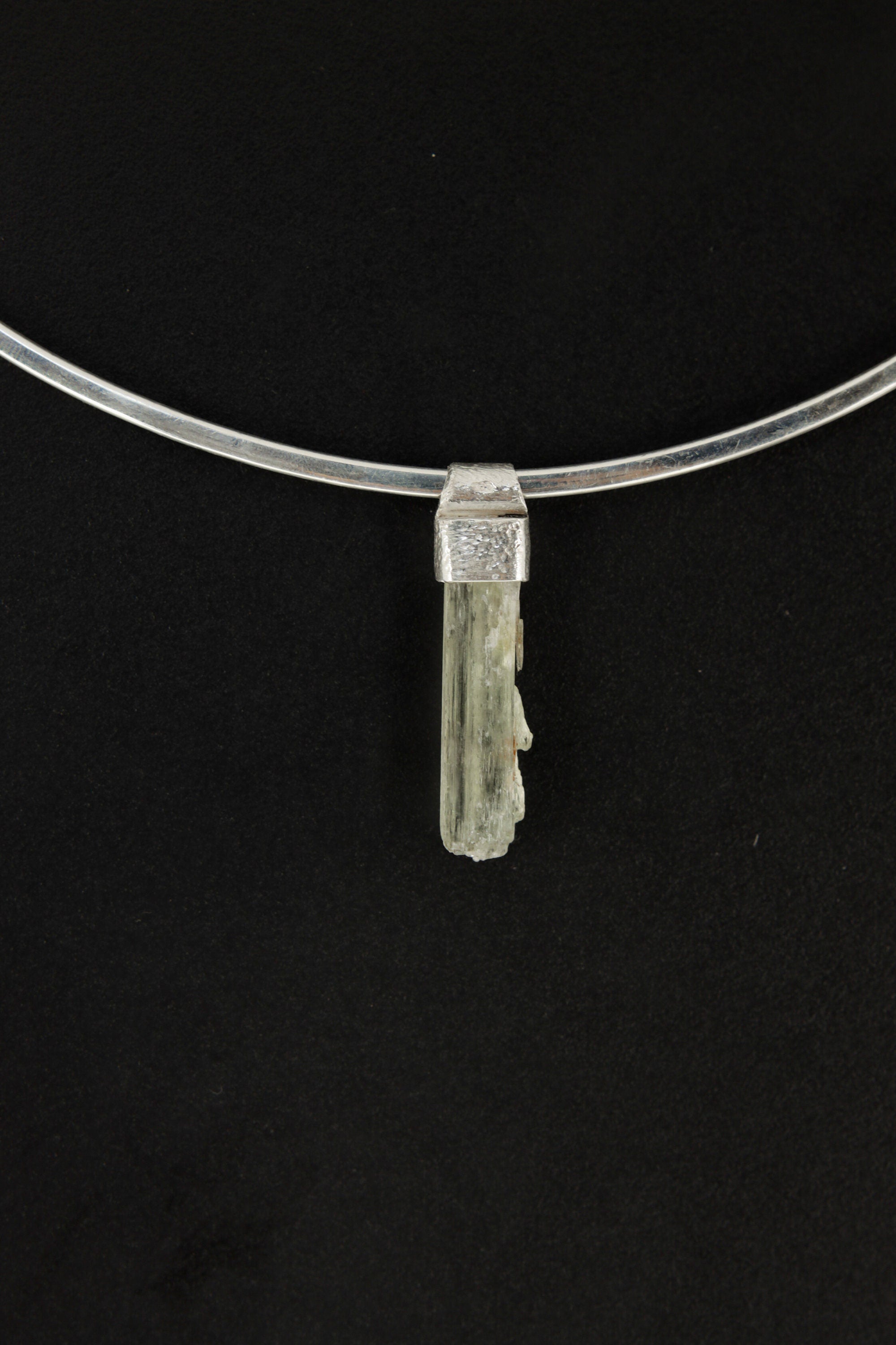 Skeletal Aquamarine Stack Pendant shown on black background with hand-hammered silver cap and slim raw crystal.