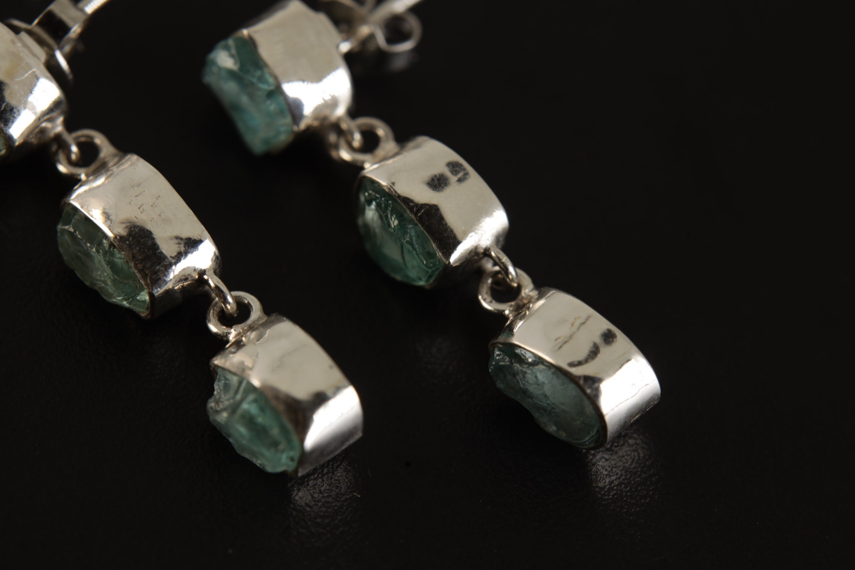 Close view of Blue Apatite earrings showing square stones, triangle lower stones, and polished silver bezel settings.