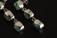 Close view of Blue Apatite earrings showing square stones, triangle lower stones, and polished silver bezel settings.
