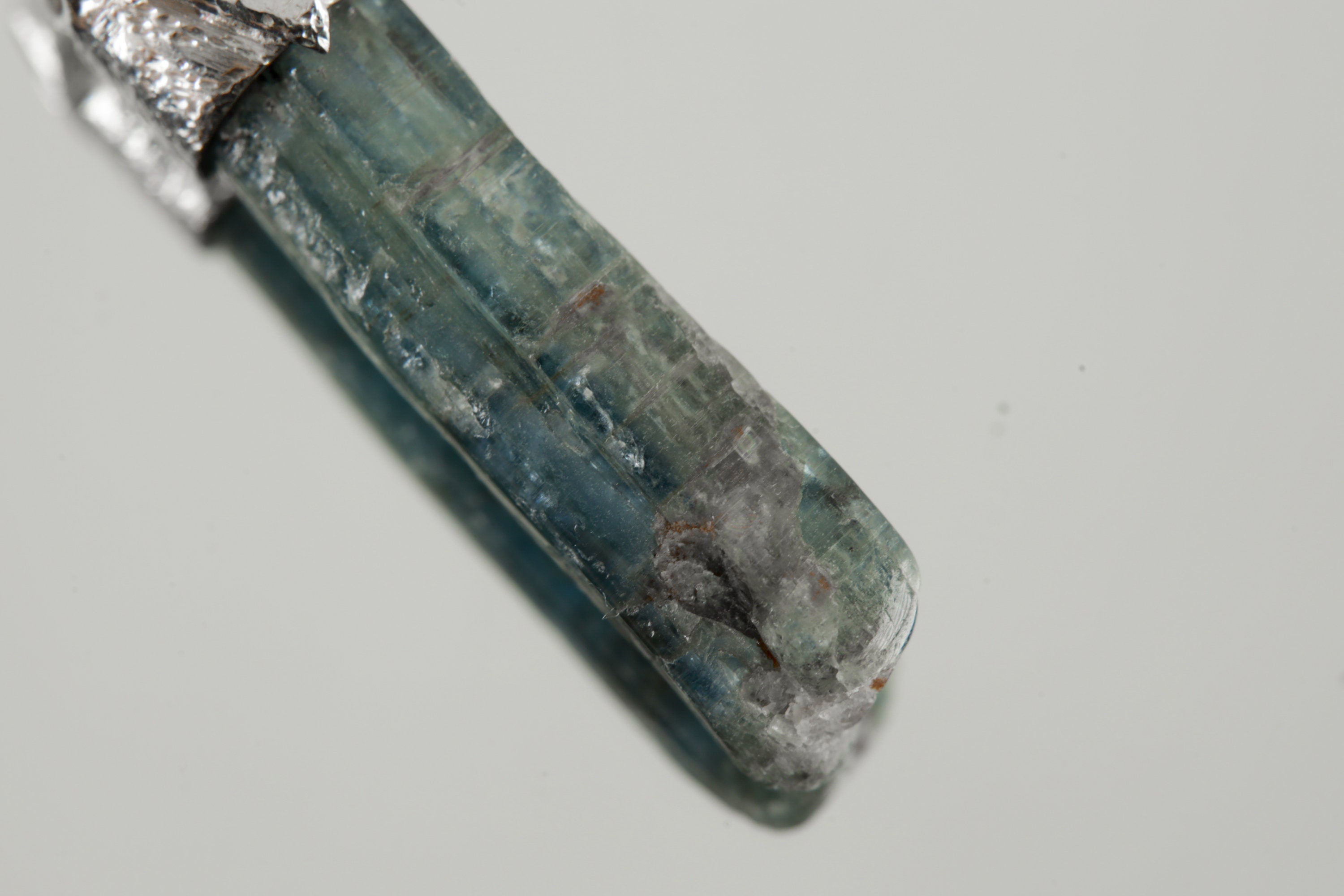 Close-up of Kyanite showing blue bladed mineral texture, natural surface detail, and organic silver cap.
