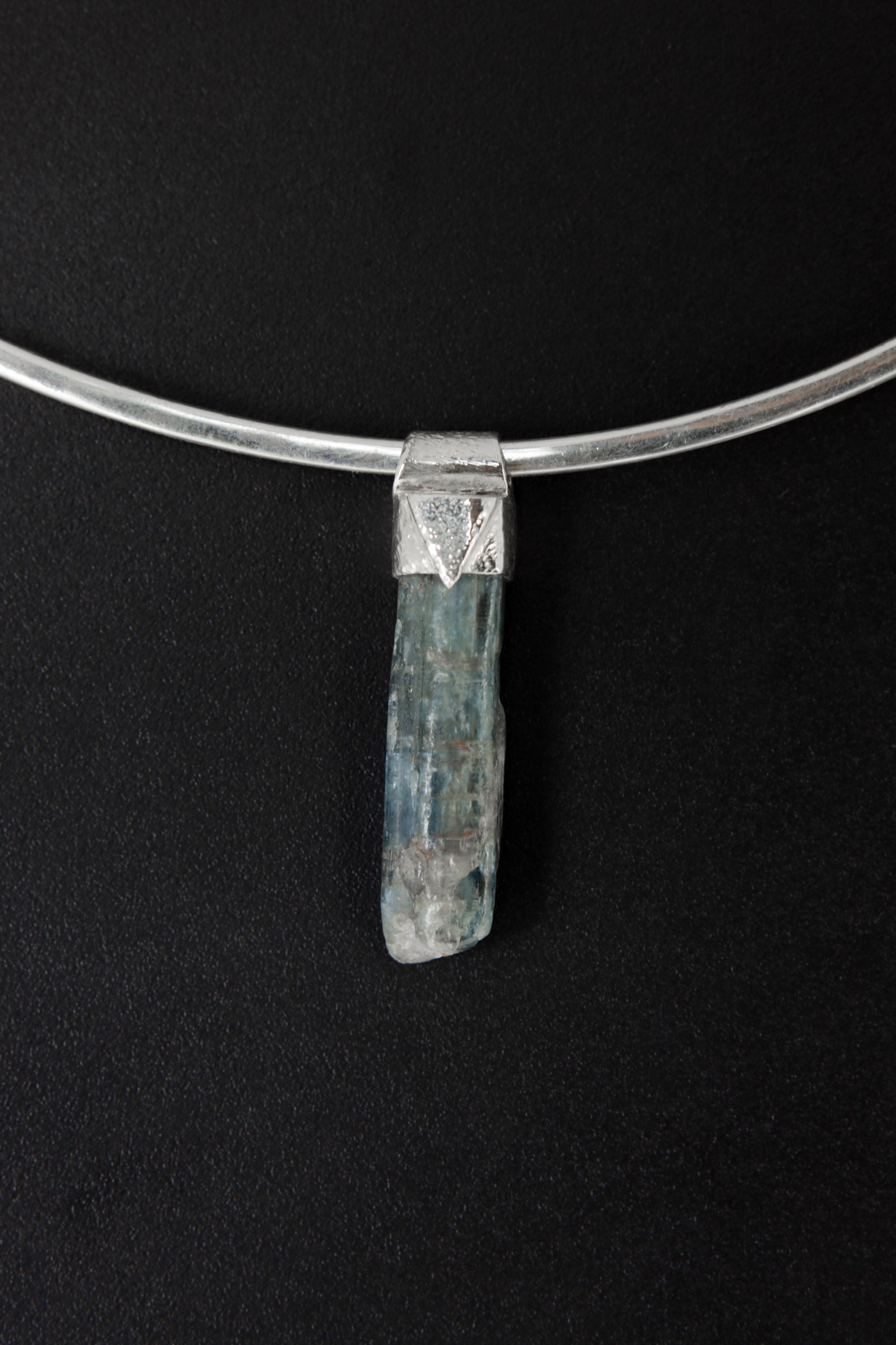 Kyanite Stack Pendant shown on black background with silver choker and slim blue crystal body.