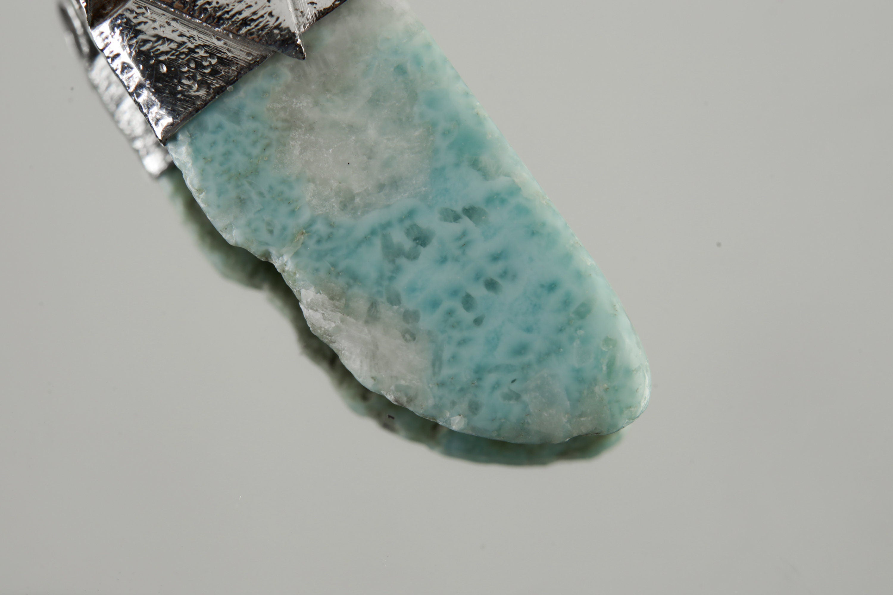 Close-up of Larimar showing soft blue-green colour, natural cloud-like patterning, and textured silver cap.