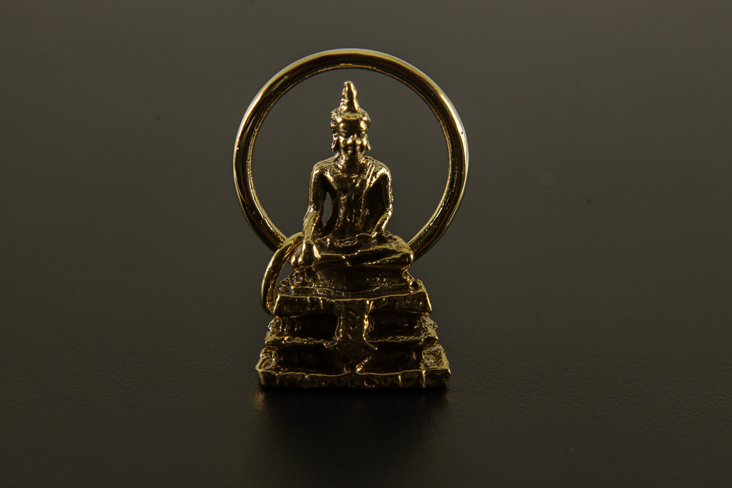 Zenith Aureate Bodhi pendant shown on a dark background, with warm golden brass finish and symbolic spiritual form.