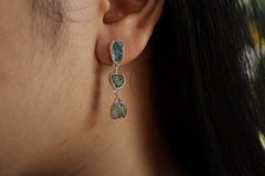 Blue Apatite stud drop earrings shown worn on the ear, with vivid blue stones and polished sterling silver settings.