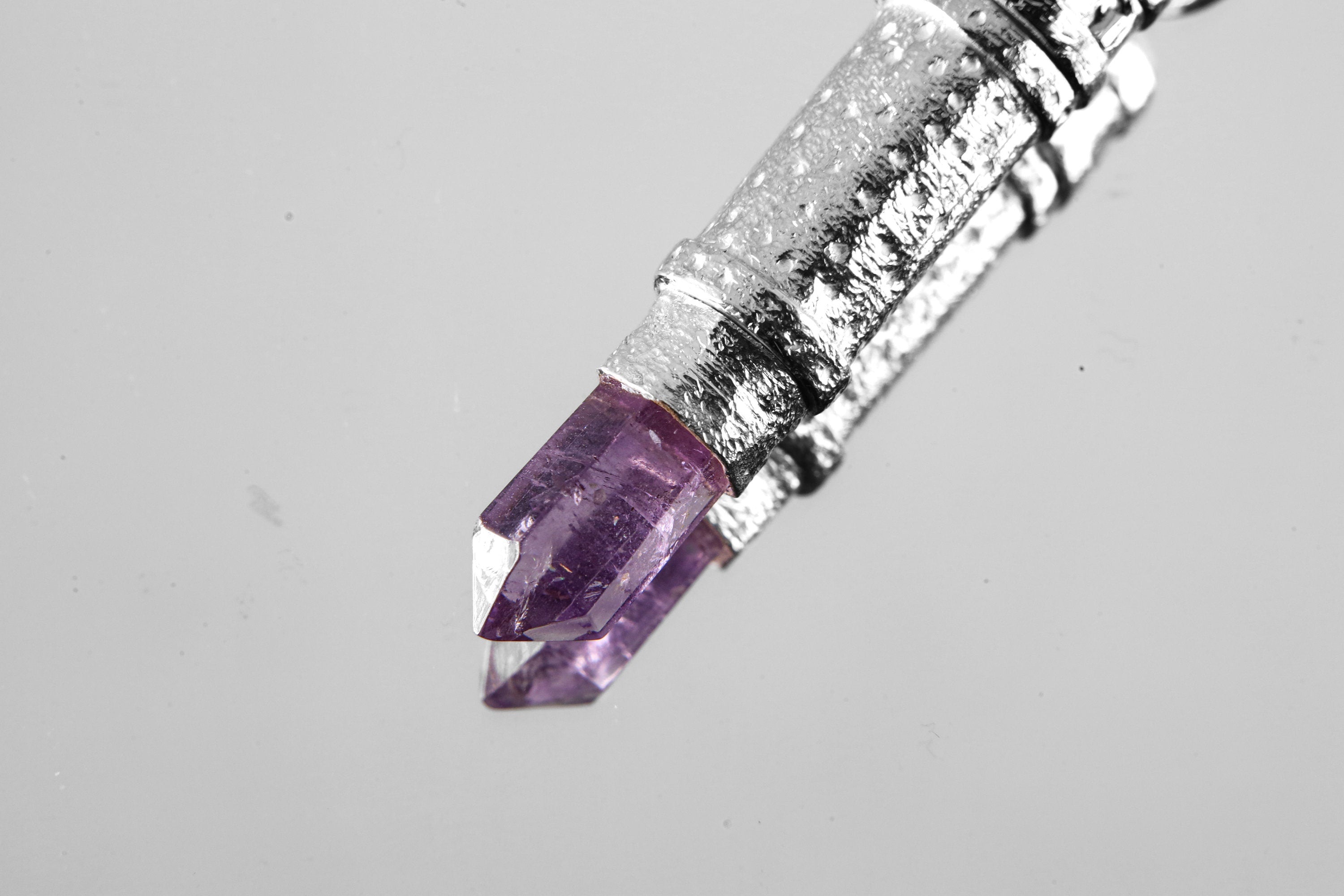 Close view of raw Vera Cruz Amethyst Point set into sterling silver capsule pendant.