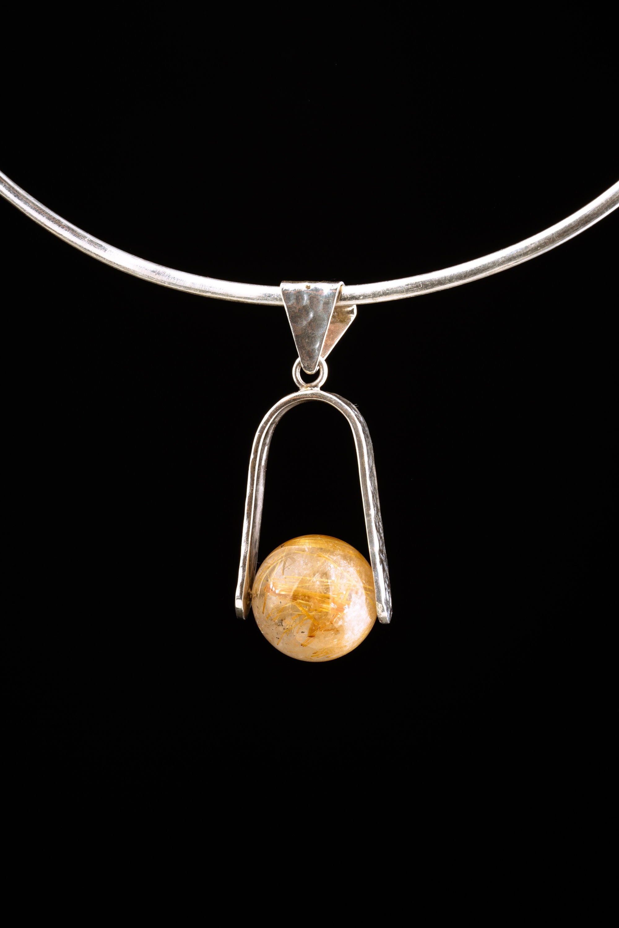 Golden Rutilated Quartz pendant displayed on silver choker against black background.