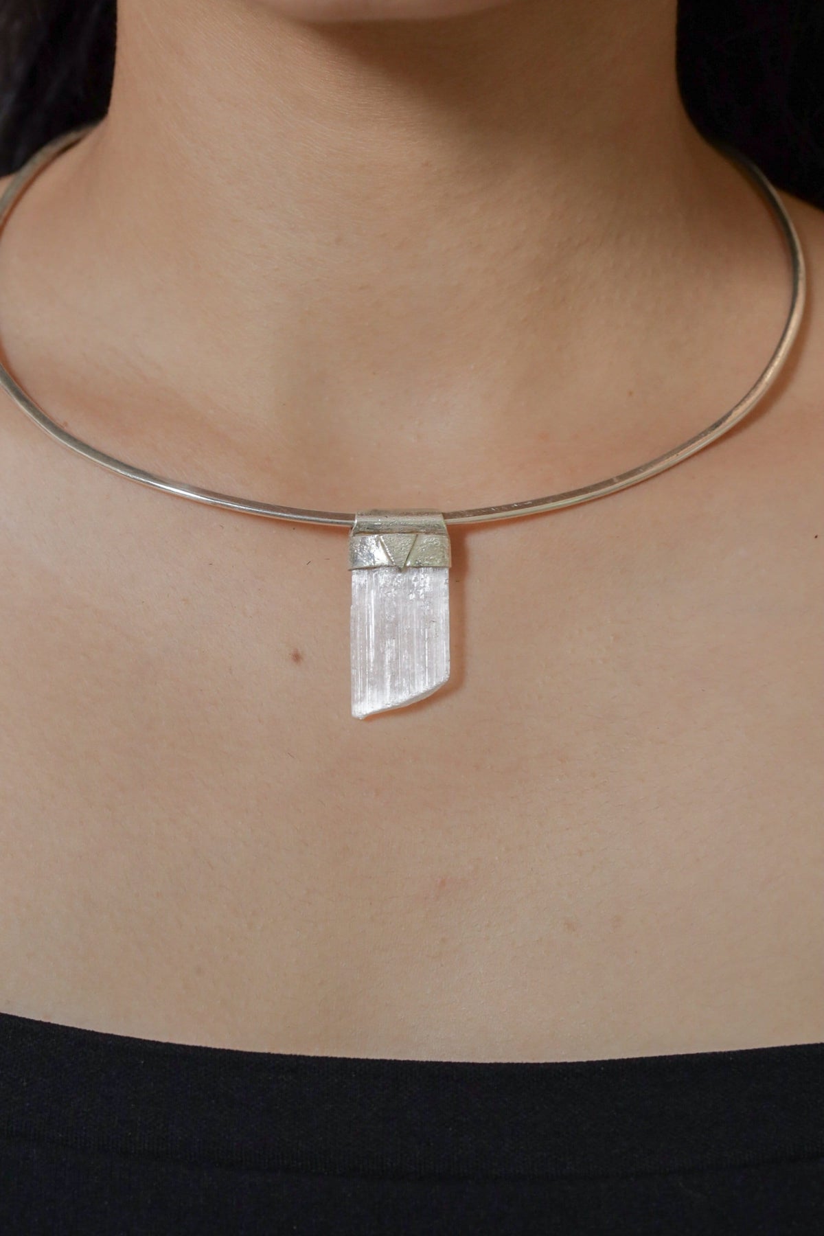 Translucent Selenite Stack Pendant shown worn on the chest with sterling silver cap and soft white crystal glow.