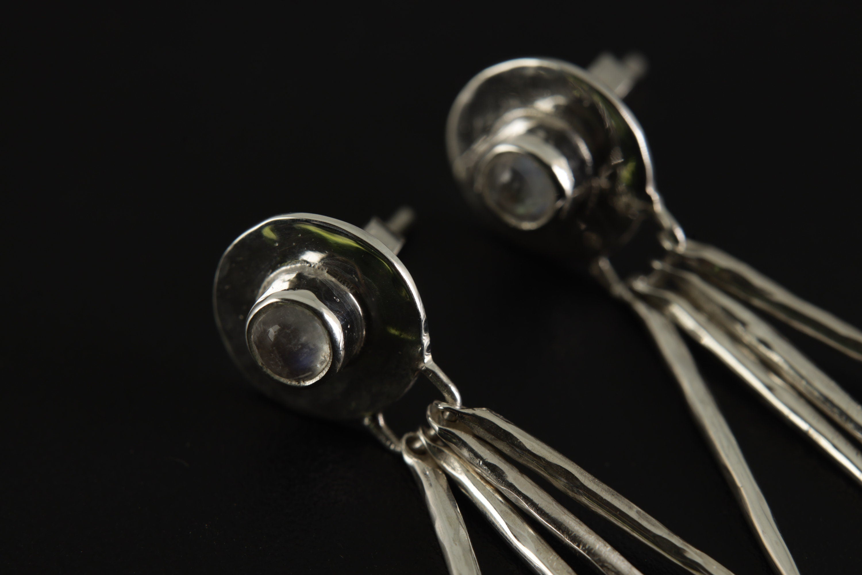 Close view of Blue Moonstone drop earrings showing hammered sterling silver texture, circular settings, and moving stick dangles.