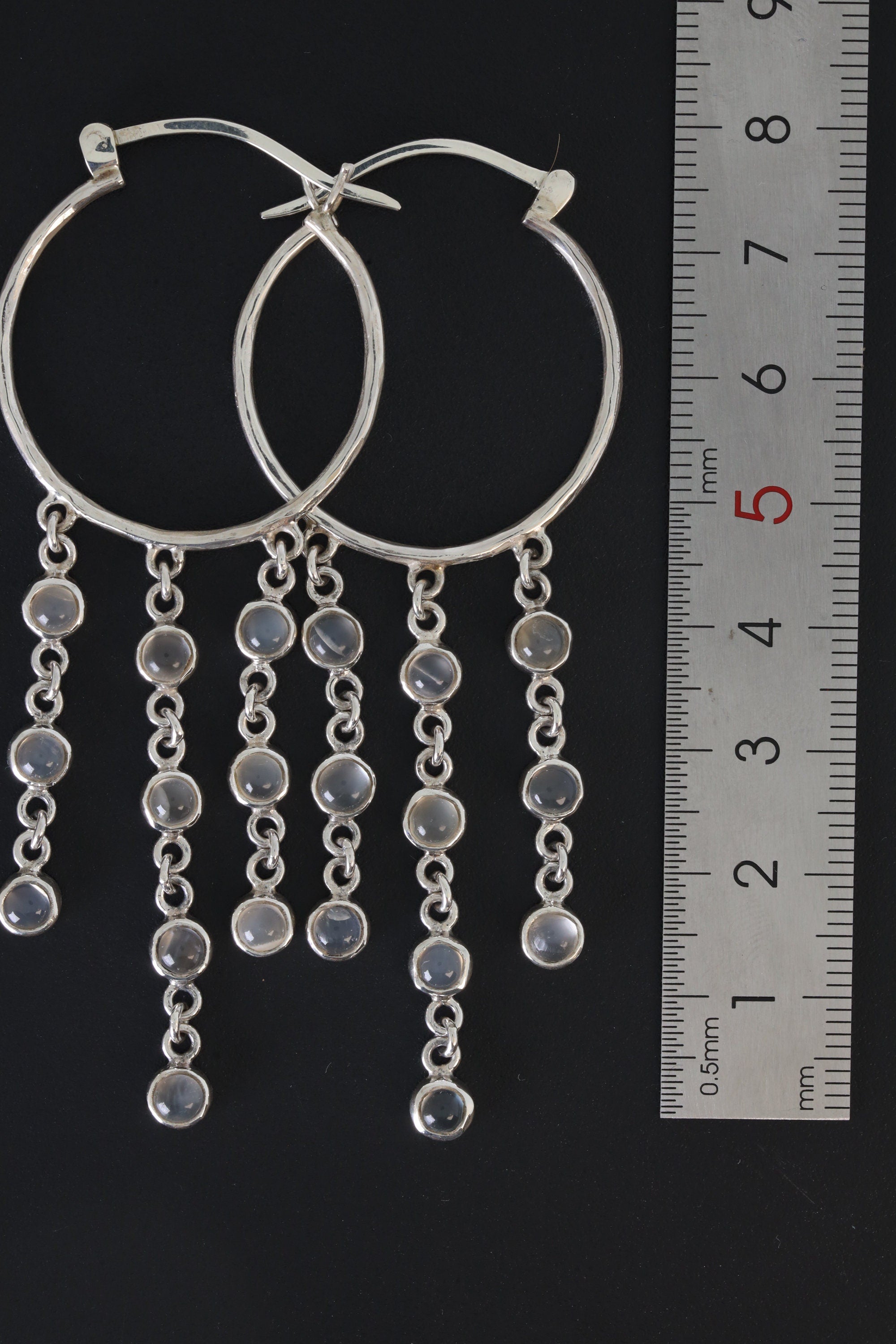 Cat Eye Moonstone cascading hoop earrings shown beside a ruler for scale, with polished sterling silver hoops.