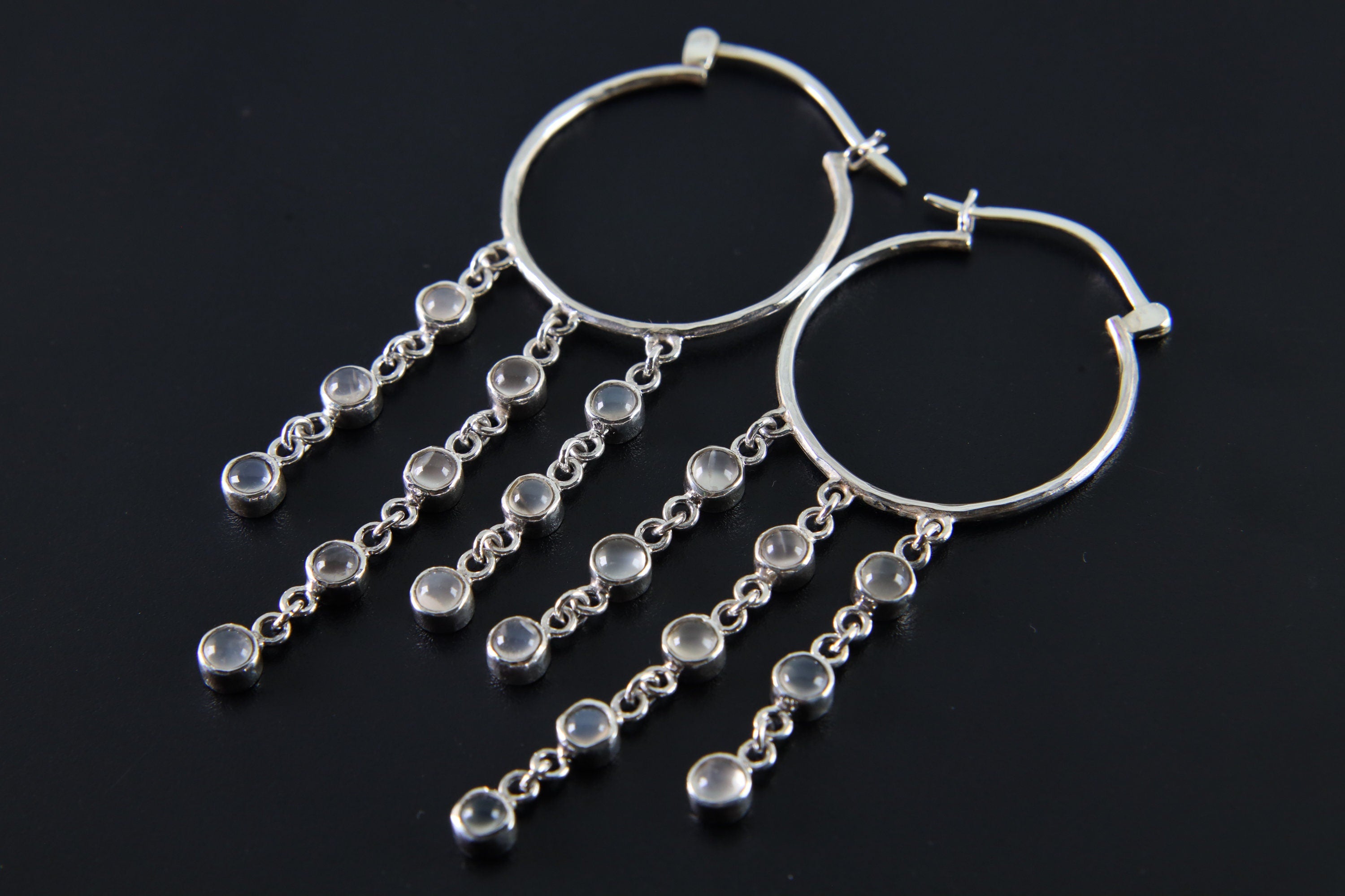 Cat Eye Moonstone hoop earring shown on a dark background with large silver hoop and cascading gemstone chains.