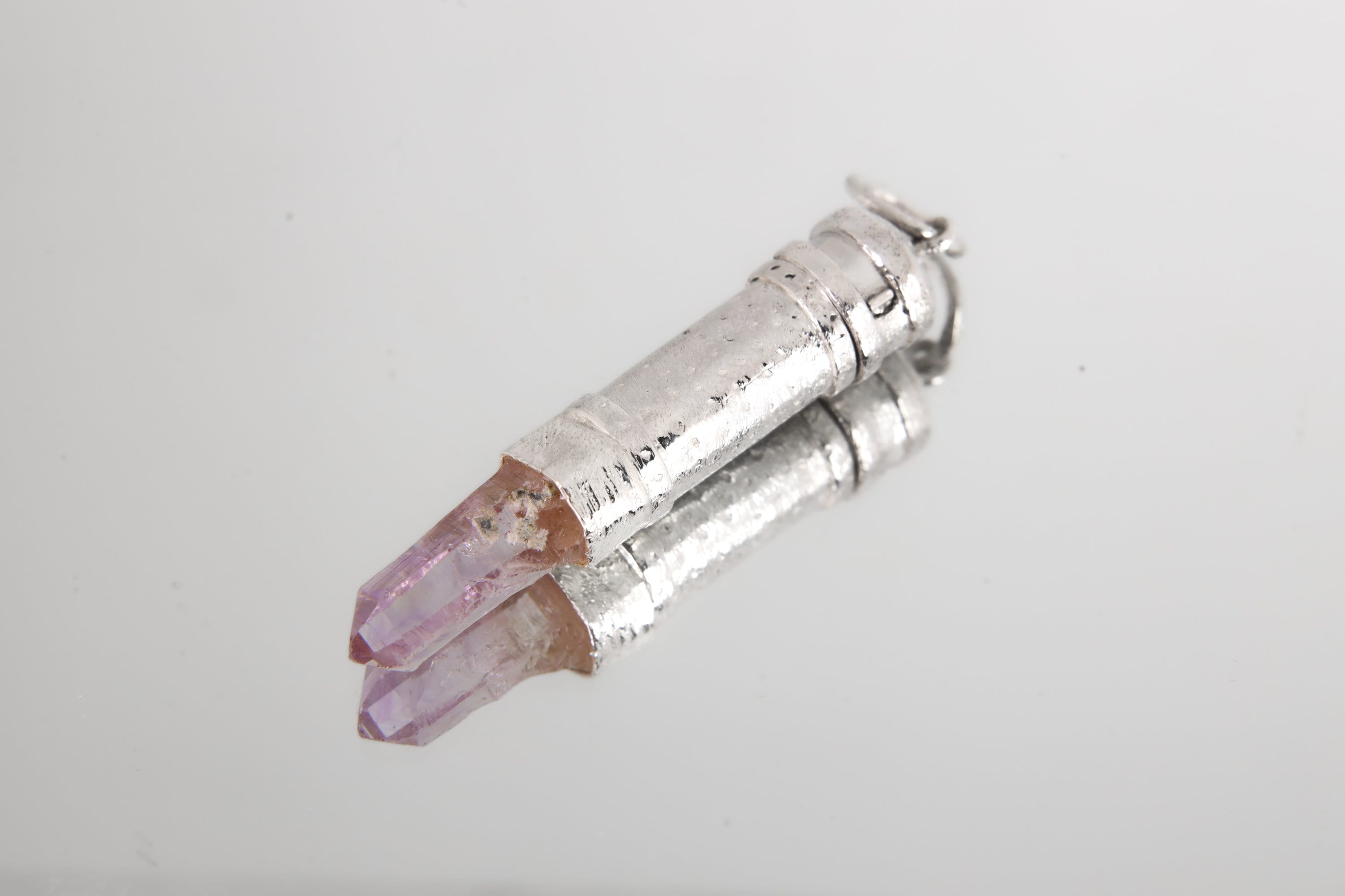 Vera Cruz Amethyst capsule pendant shown on white background with polished 925 sterling silver and raw crystal point.