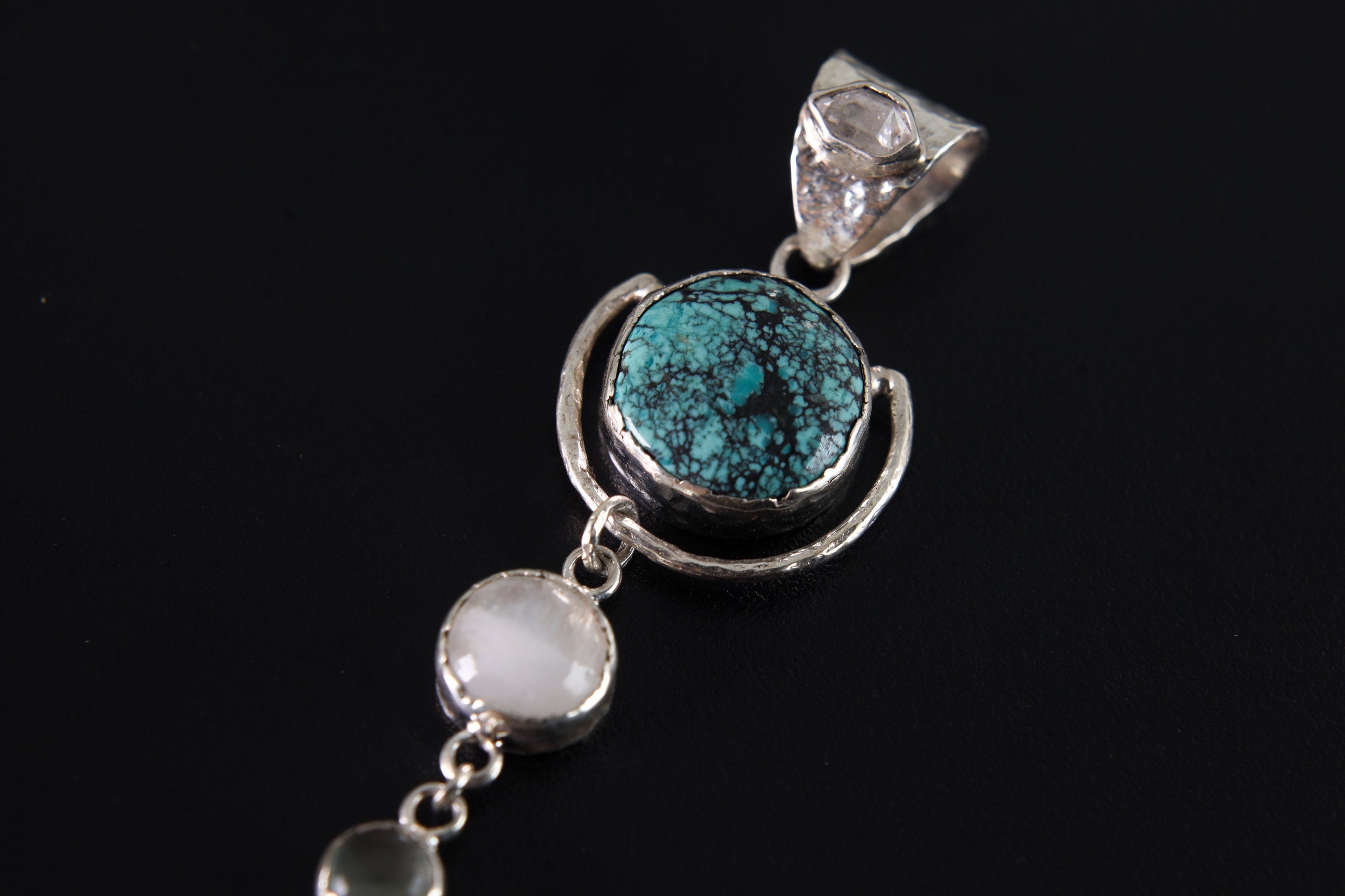 Close-up of Turquoise orb and Moonstone dangles in a polished 925 sterling silver celestial pendant.
