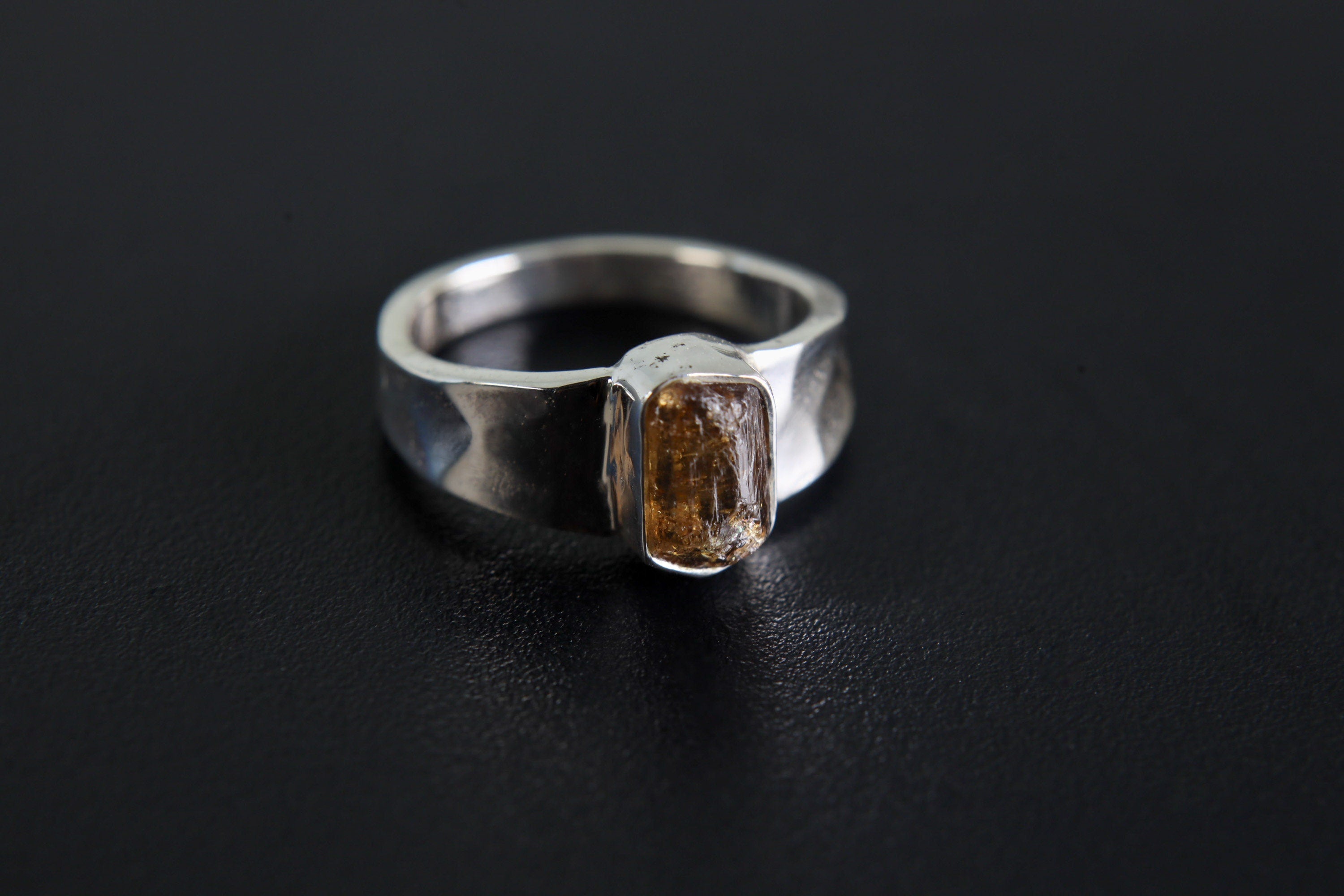 Brown Tourmaline Terminated Ring shown on black background with shiny hammered silver band and raw brown crystal.