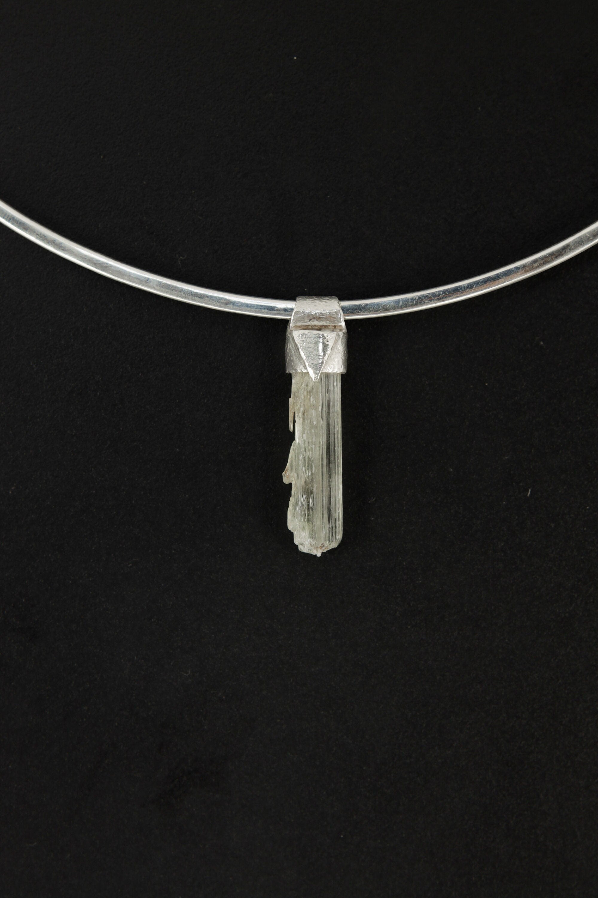 Skeletal Aquamarine Stack Pendant shown on black background with sterling silver cap and raw green-blue crystal body.