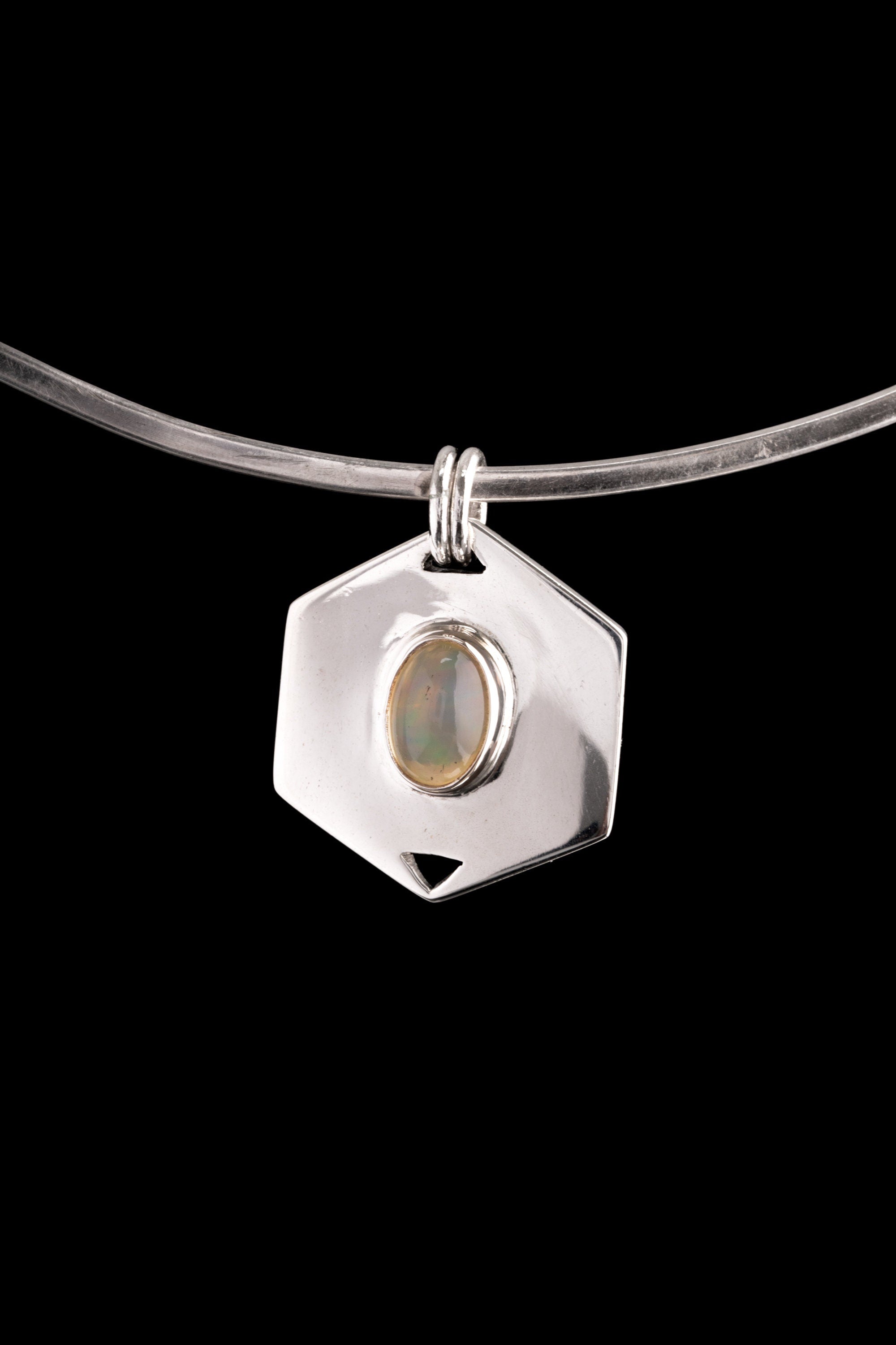 Ethiopian Opal hexagon pendant displayed on a choker against dark background with polished silver frame.