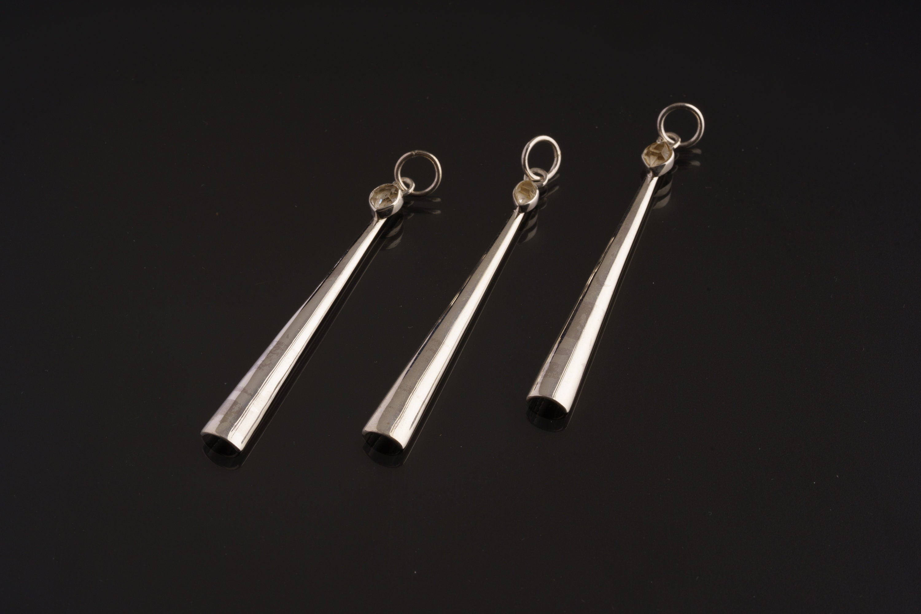 Three Herkimer Diamond spoon pendants shown together on dark background with polished sterling silver scoop forms.