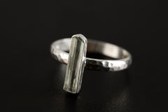 Side view of long Aquamarine silver ring showing polished hammered band and raised gemstone setting.