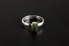 Green Tourmaline hammered silver ring shown on a dark background, with vertical green gemstone and polished 925 sterling silver band.