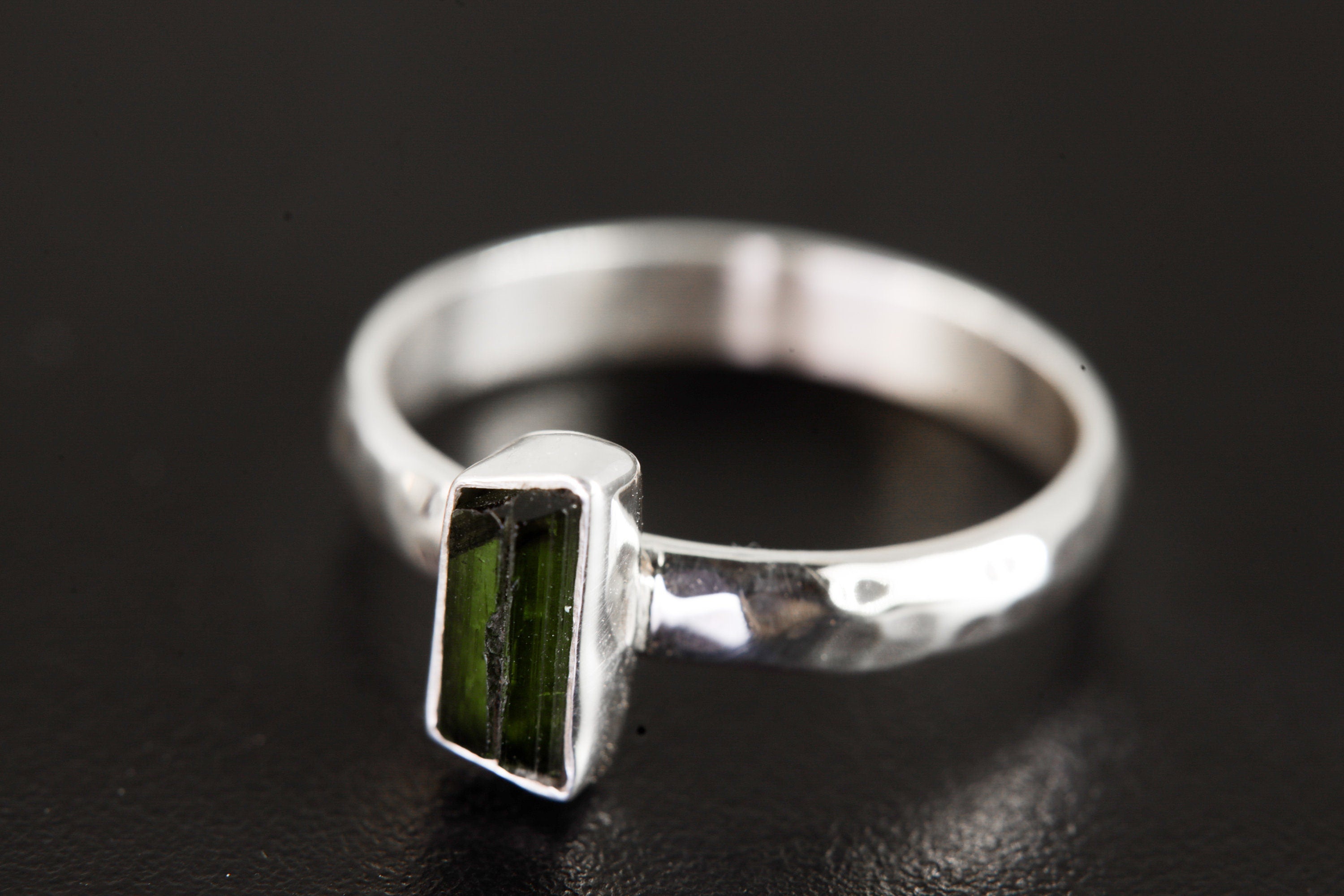 Side view of Green Tourmaline silver ring showing hammered sterling silver band and slim vertical gemstone setting.