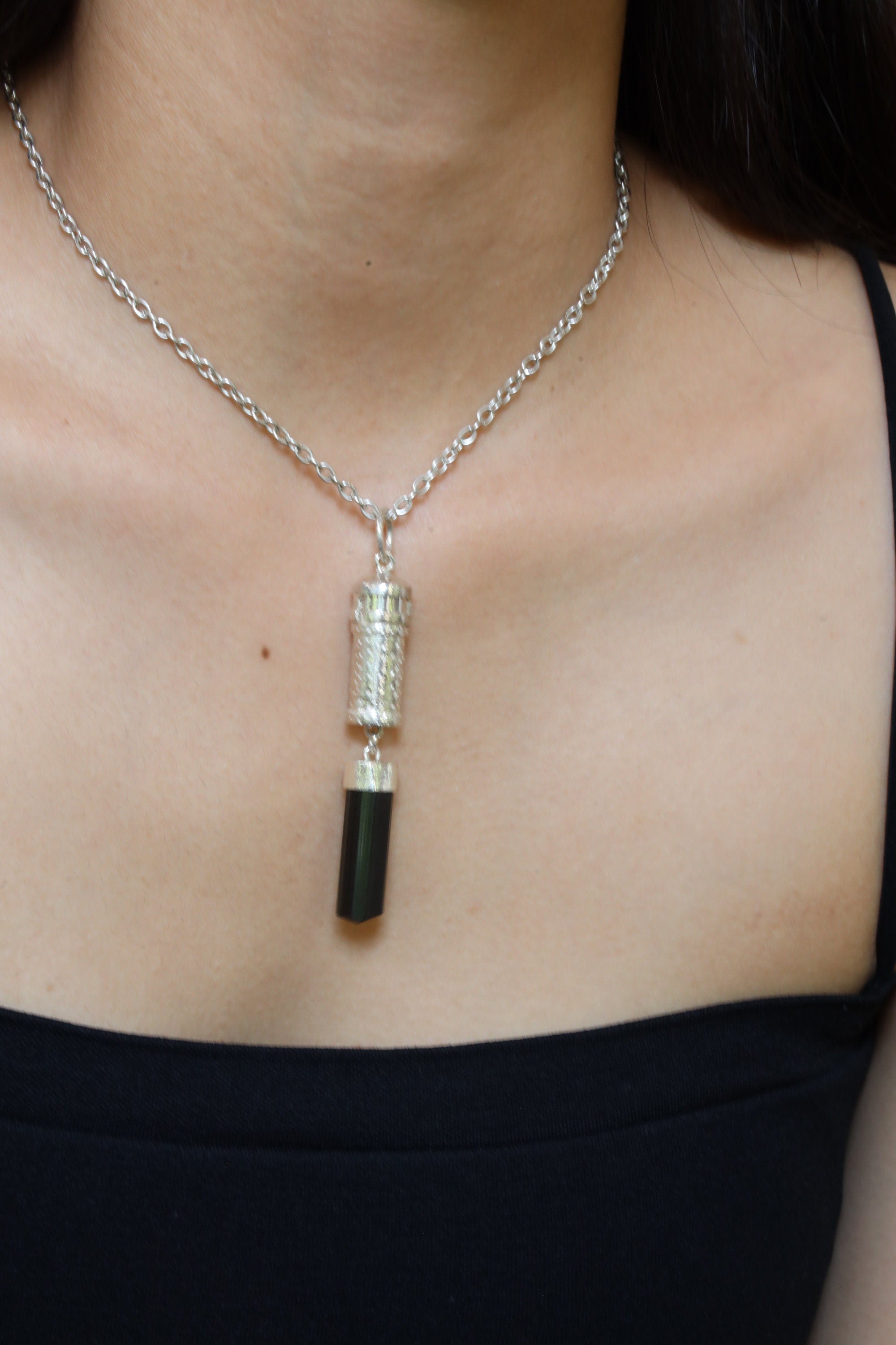 Black Tourmaline capsule pendant shown worn on a model, highlighting 8 cm statement length and polished silver finish.