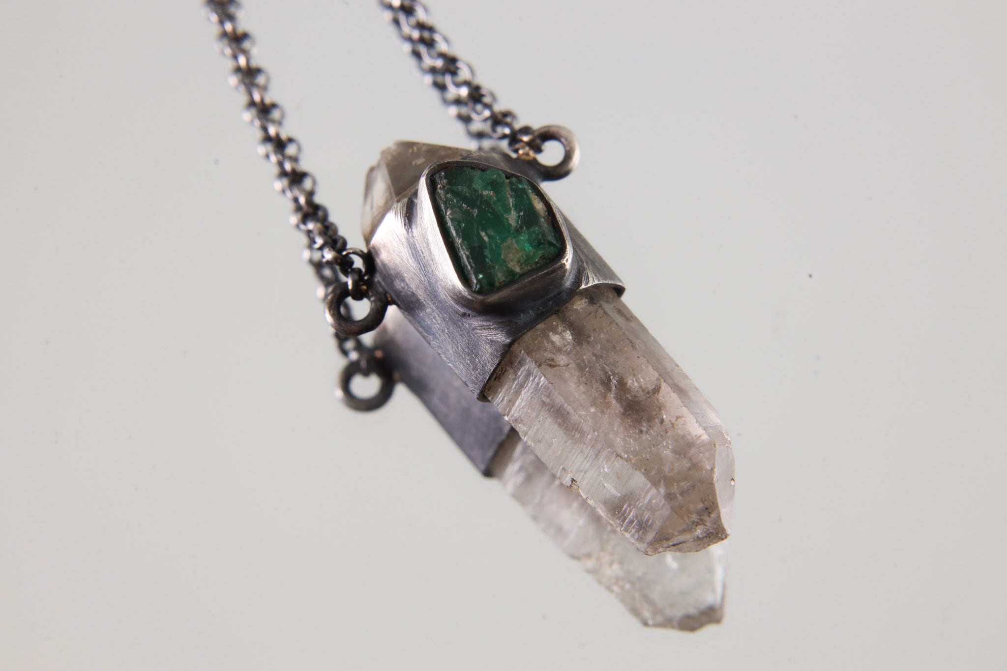 Vera Cruz Amethyst Emerald Pendant shown on light background with raw Australian Emerald and clear Amethyst crystal.