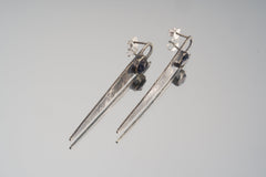 Sapphire hammered sterling silver earrings displayed on light background with long tapered oxidized silver forms.