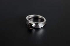 Crimson Sentinel Garnet Ring shown on black background with deep crimson stone and high-shine silver band.