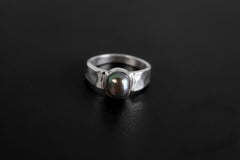 Midnight Luster Black Pearl Ring shown on black background with hammered silver band and smooth dark Pearl centre.