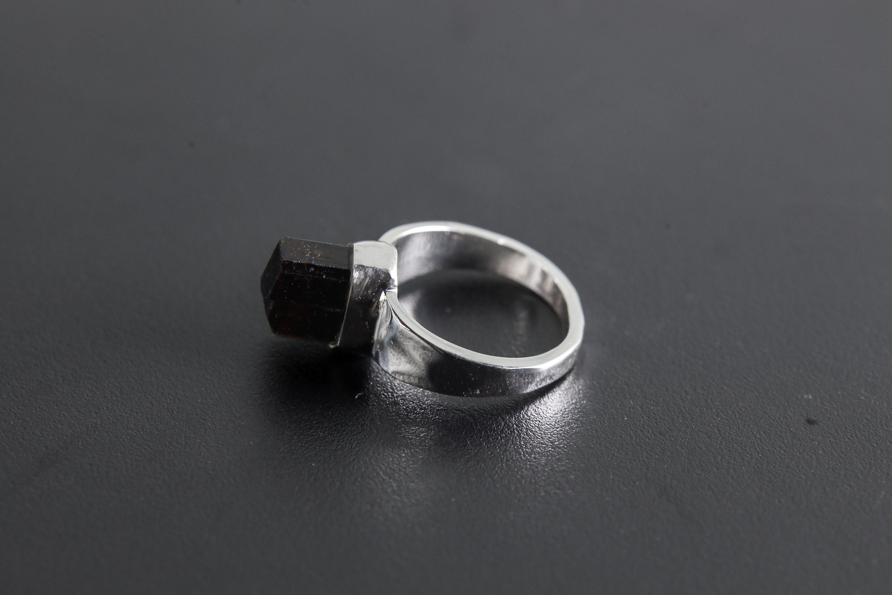 Side view of handmade Black Tourmaline ring showing the raised raw stone, bezel setting, and polished silver band.