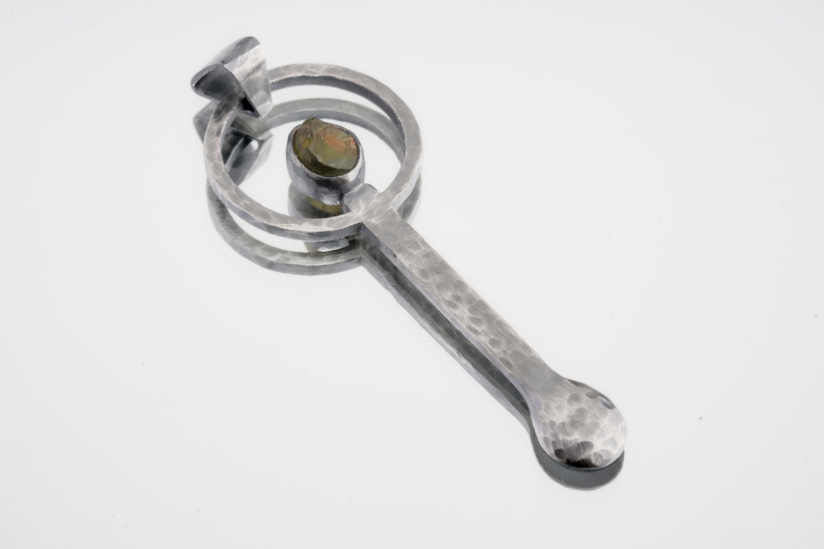 Peridot oxidized sterling silver ritual spoon shown on white background with hammered silver and green gemstone setting.