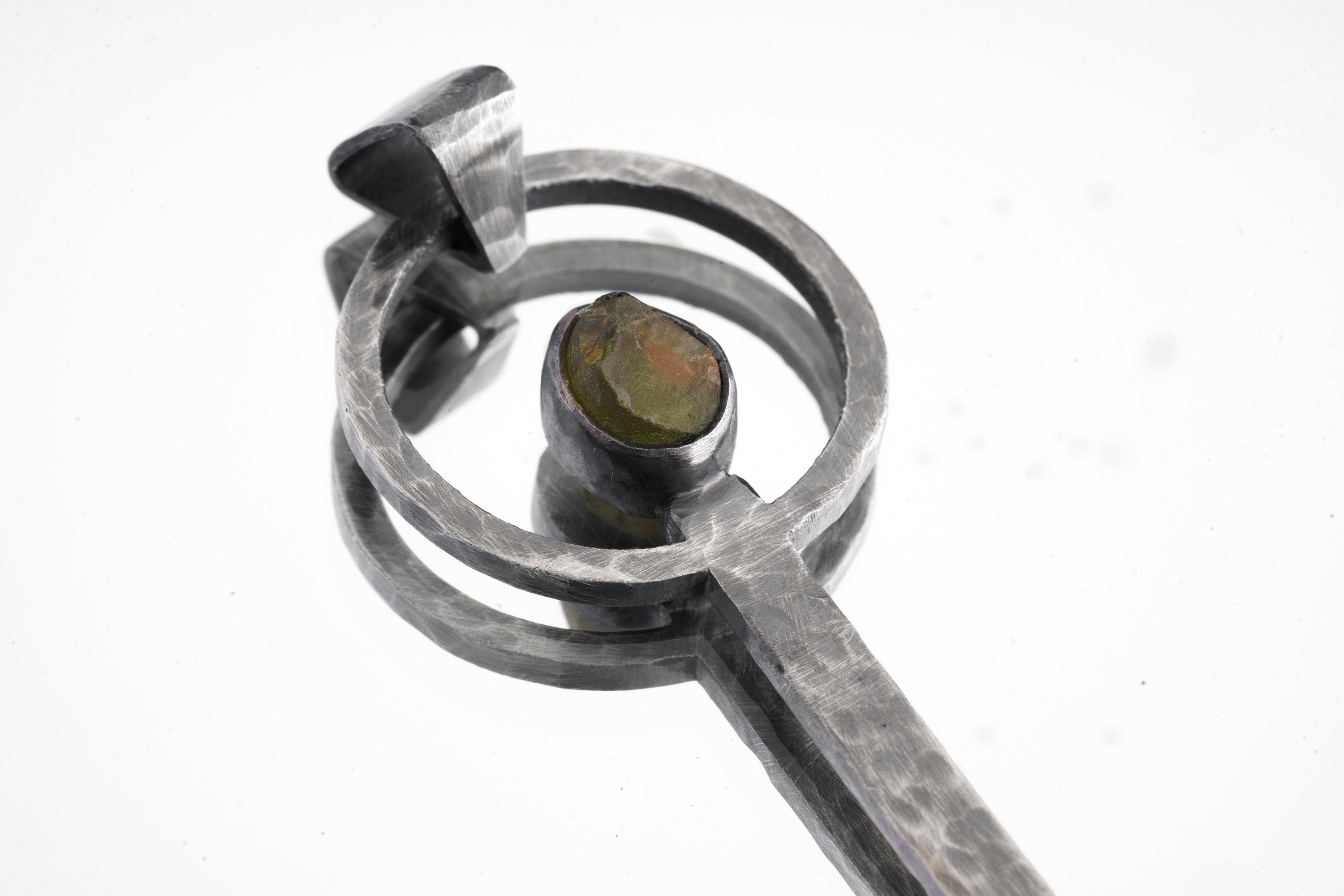 Close-up of Peridot ritual spoon showing hammered oxidized silver texture and bright green gemstone.