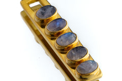 Close view of five oval Blue Moonstones set in a rectangular gold-plated brass pendant.