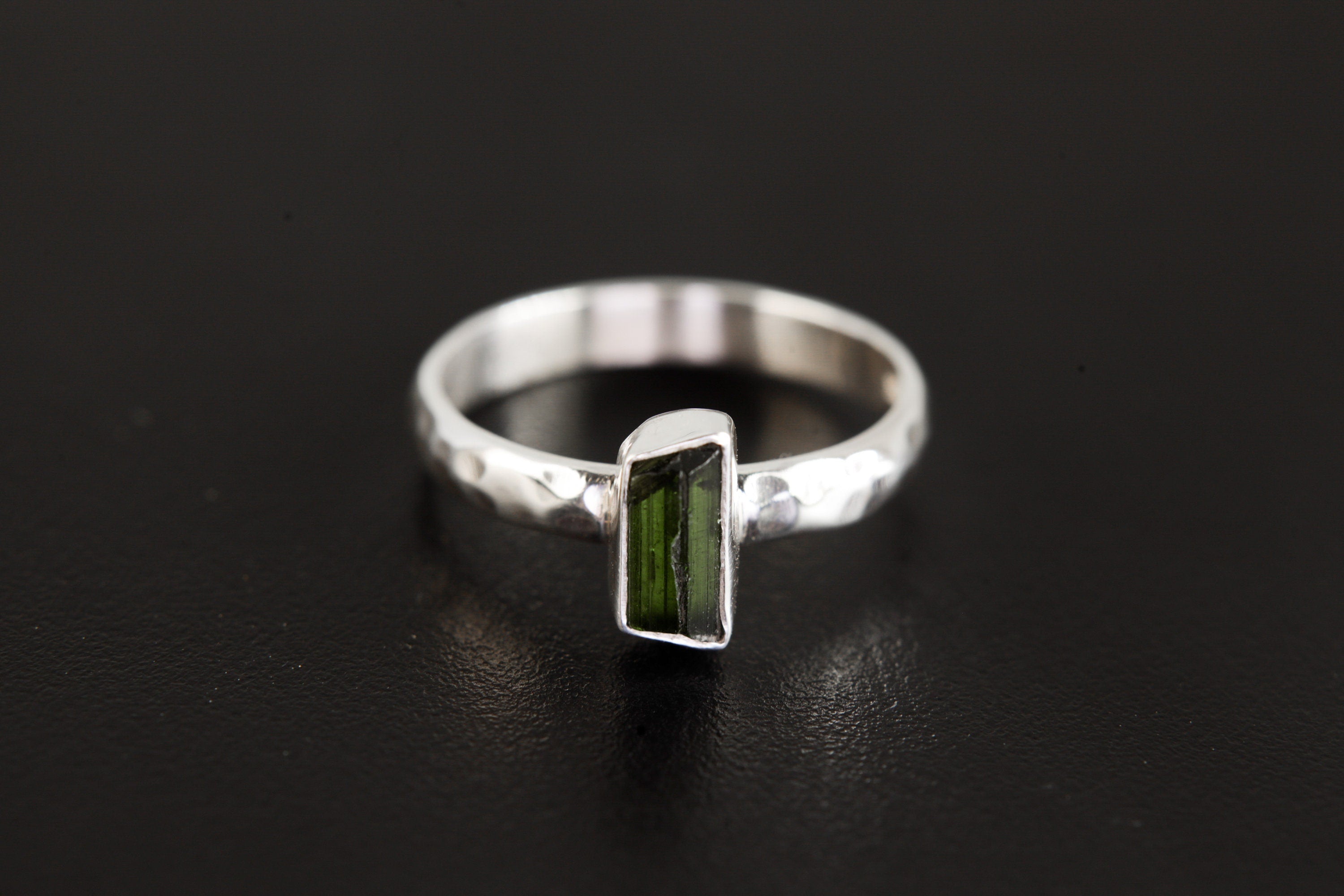 Green Tourmaline ring shown on a dark background, with polished 925 sterling silver band and vertical green stone setting.