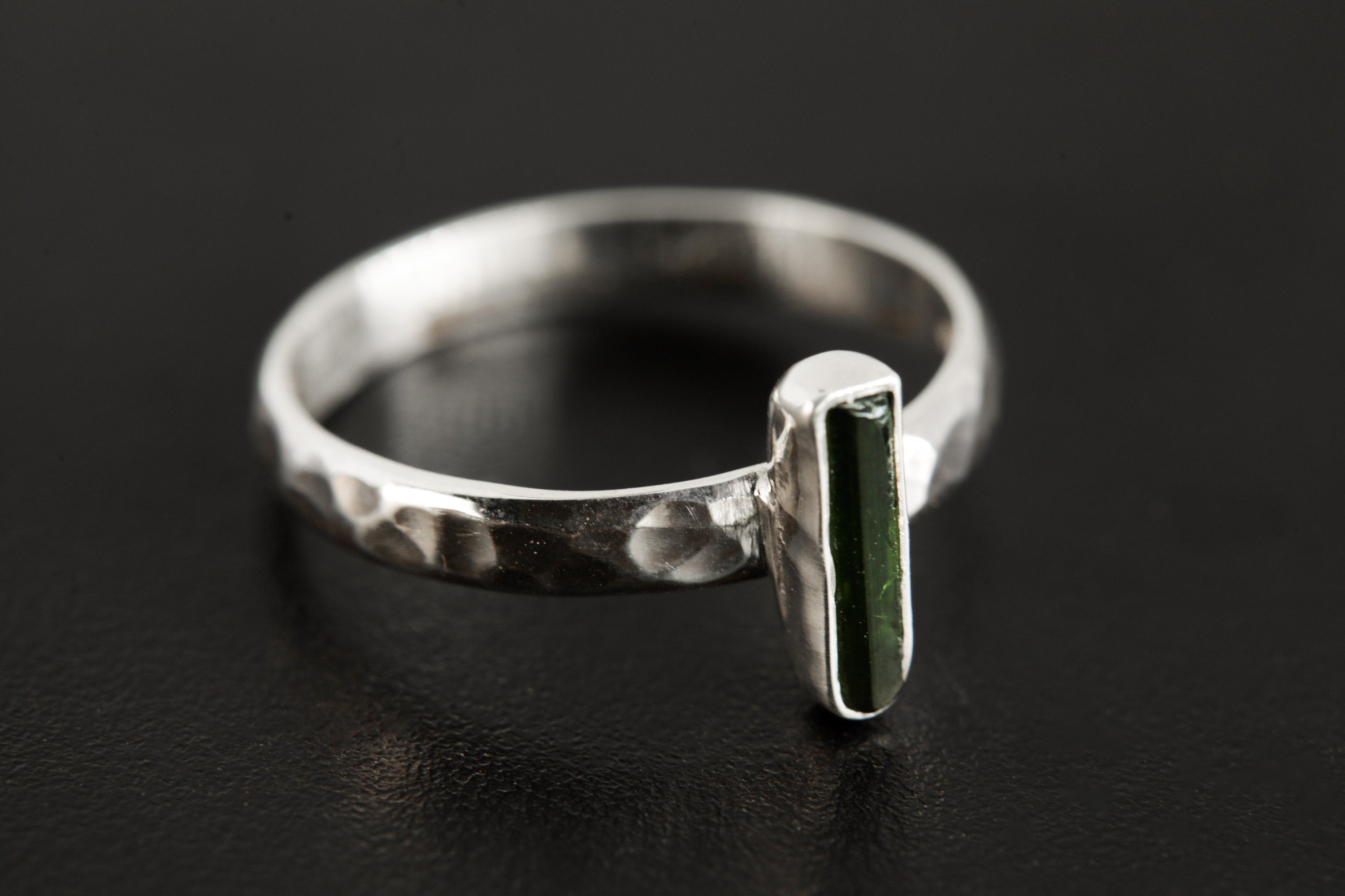 Side view of Green Tourmaline silver ring showing hammered sterling silver band and slim vertical gemstone setting.