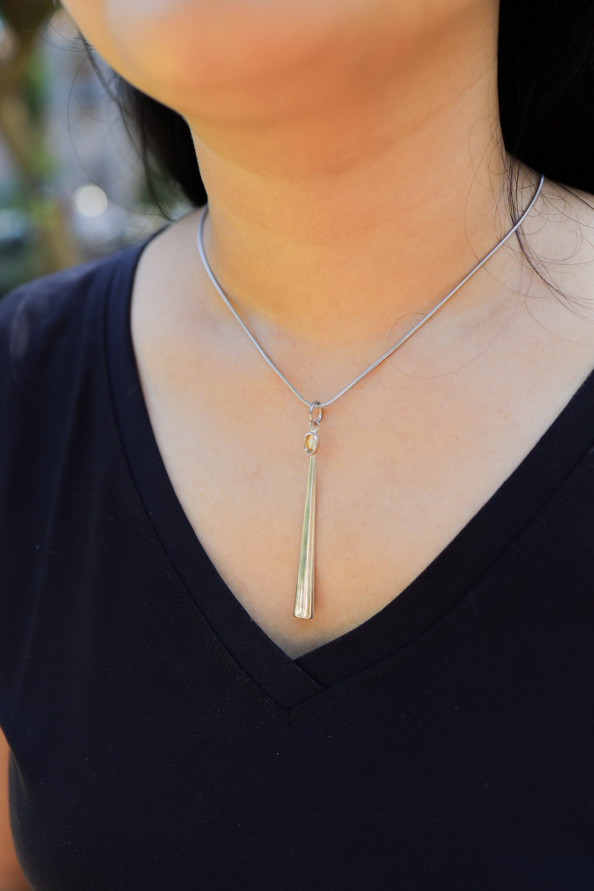 Herkimer Diamond spoon pendant shown worn outdoors on a model with polished sterling silver and crystal detail.