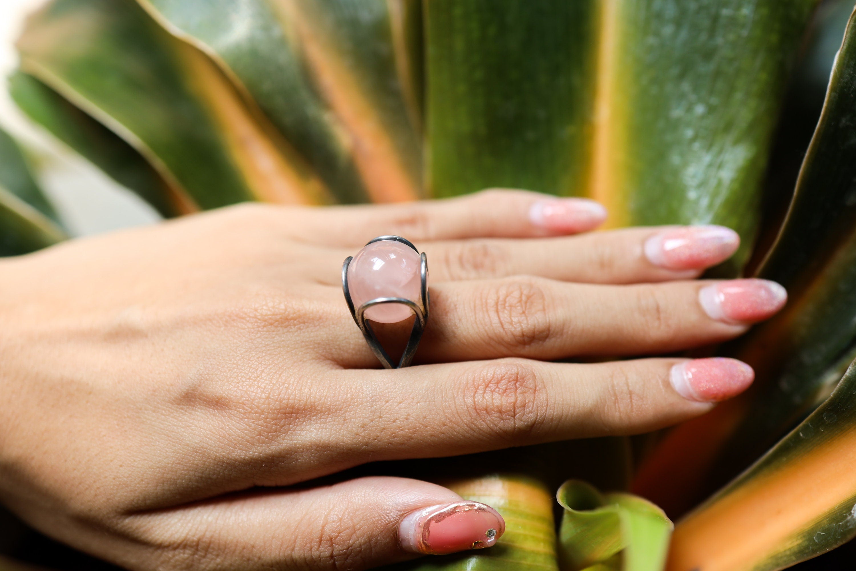 Rose Quartz Floral Silver Ring shown worn outdoors with textured oxidized silver and round pink gemstone.