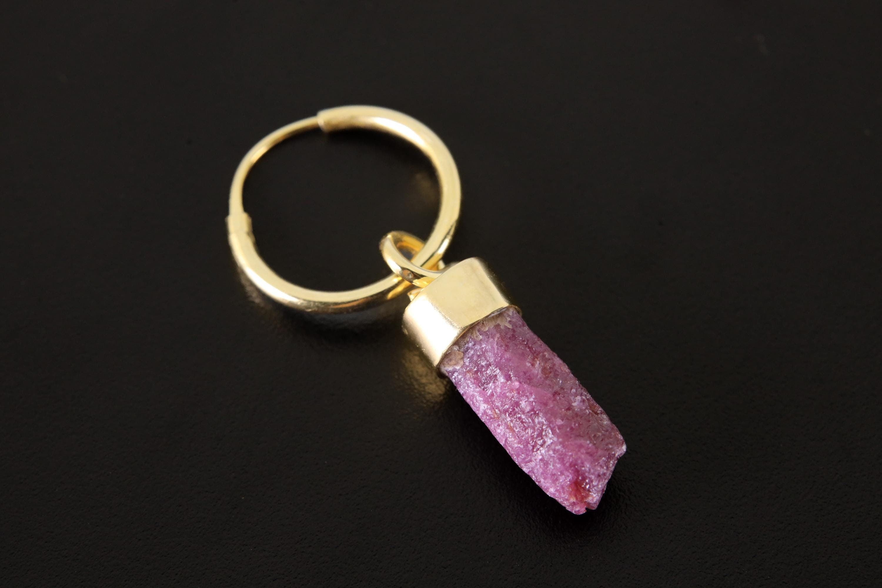 Ruby single hoop earring shown on dark background with gold-plated sterling silver and vivid pink-red crystal.