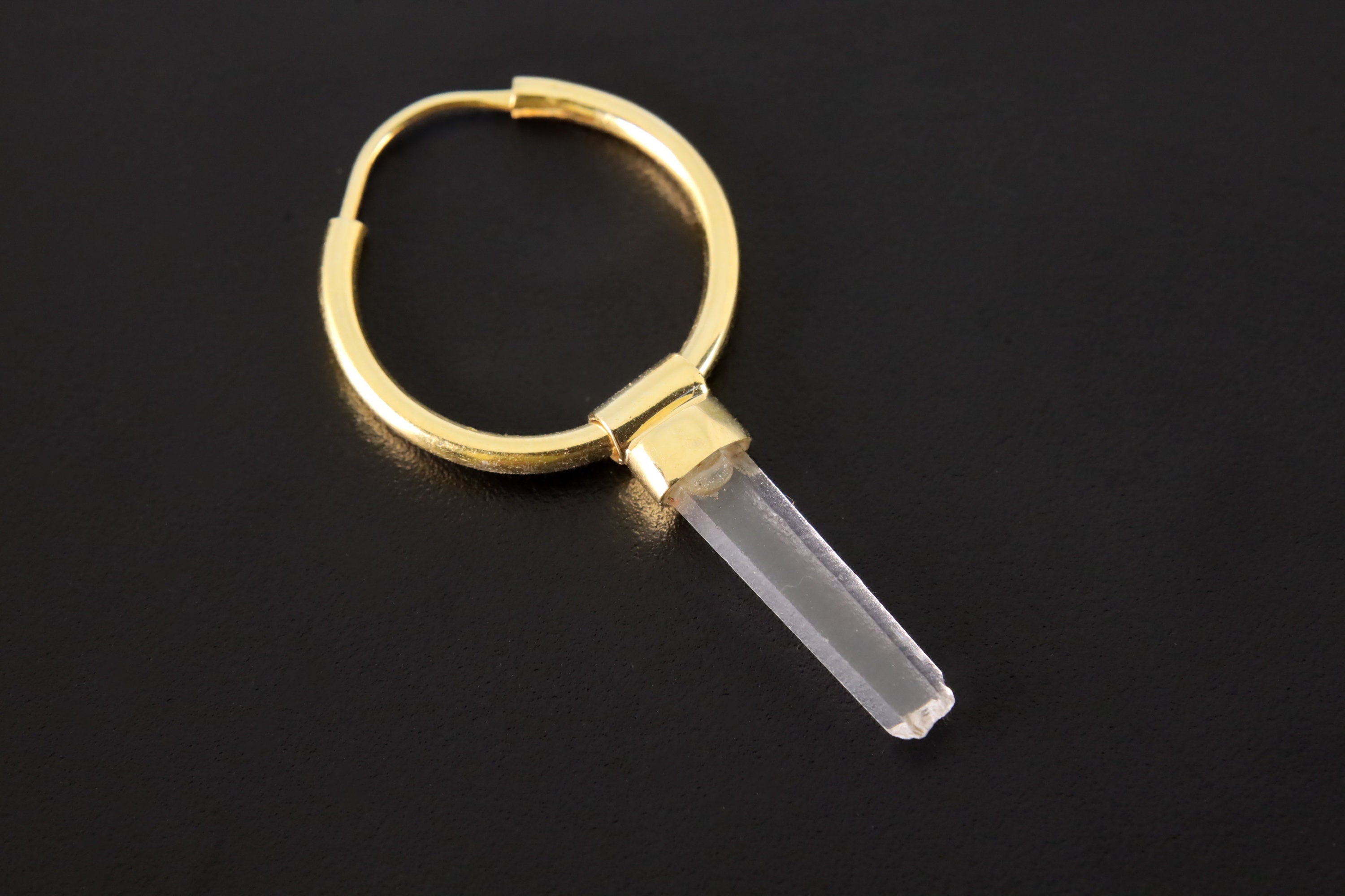Clear Quartz dangle hoop earring shown on dark background with gold-plated sterling silver and transparent crystal.