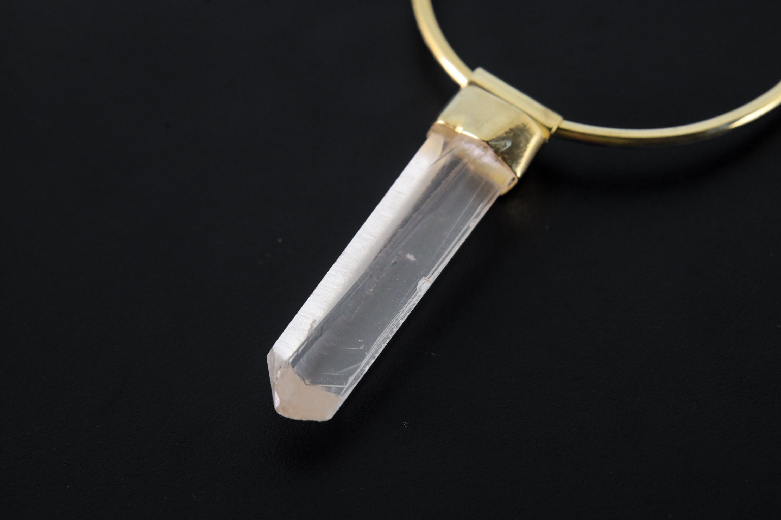 Close-up of Lemurian Quartz hoop earring pendant showing clear crystal striations and warm gold-plated setting.