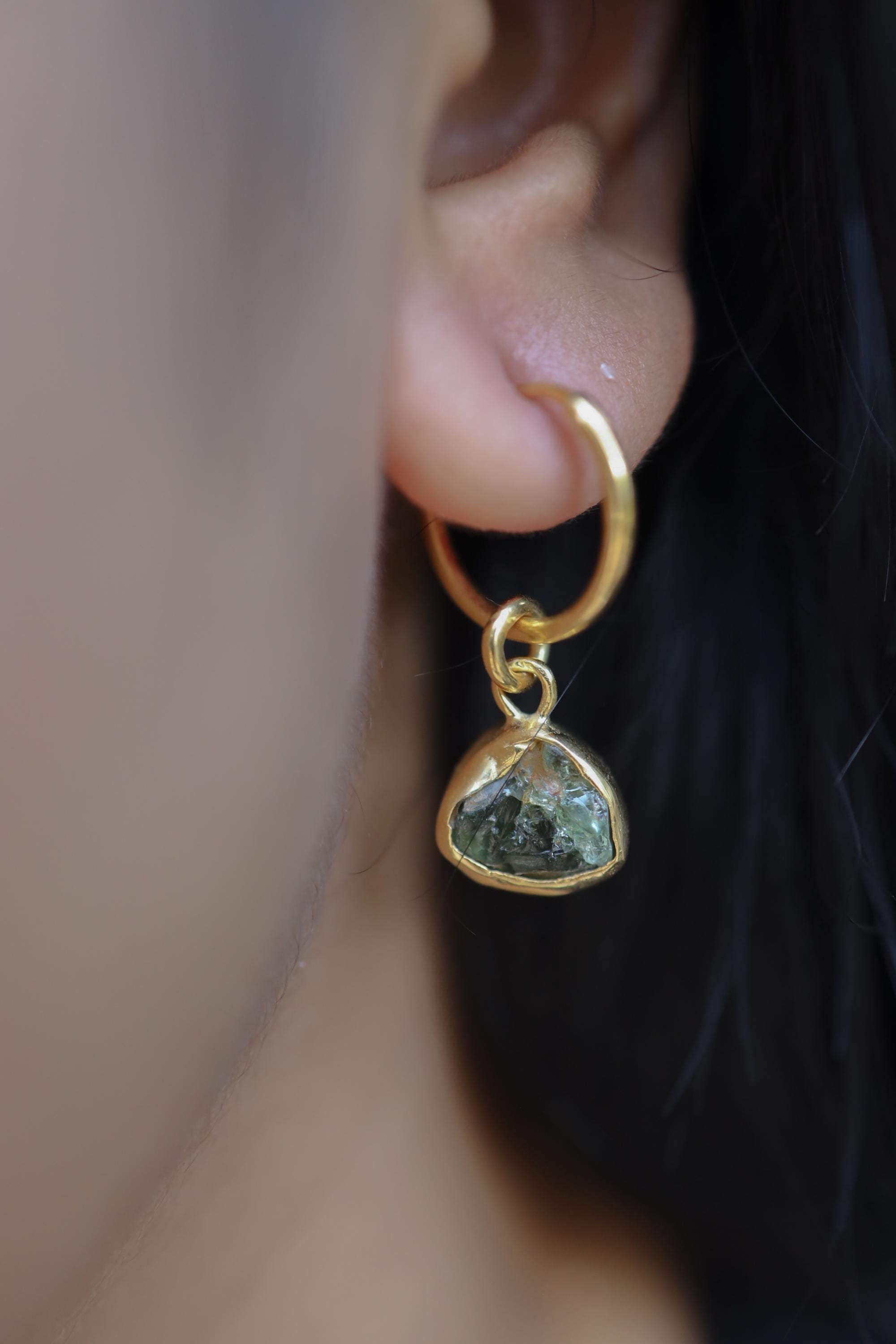 Green Tourmaline gold-plated hoop earring worn on a model, showing single-piece convertible charm styling.