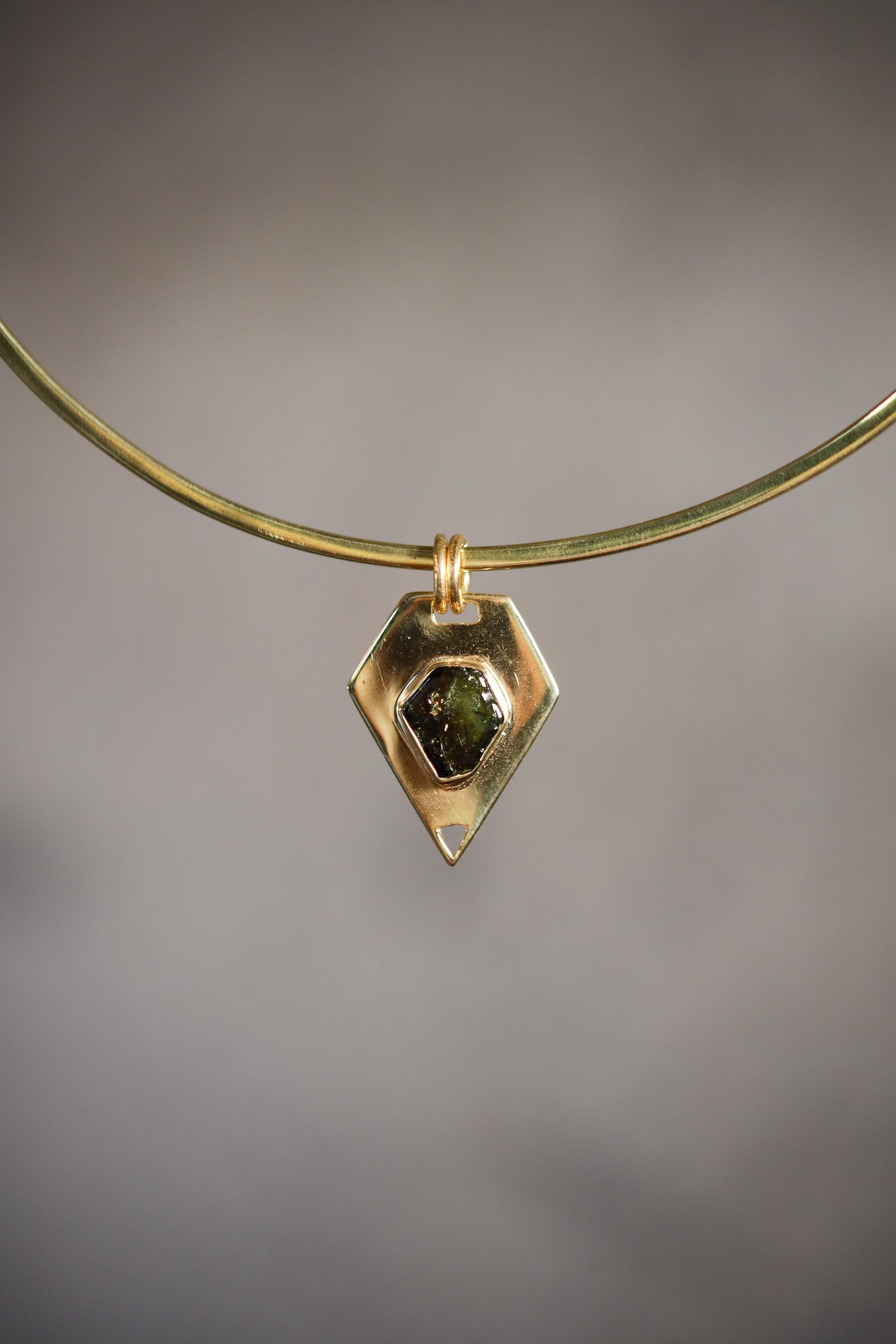Small Green Tourmaline slice pendant shown on a gold-toned necklace, with organic pentagonal shape and warm gold setting.