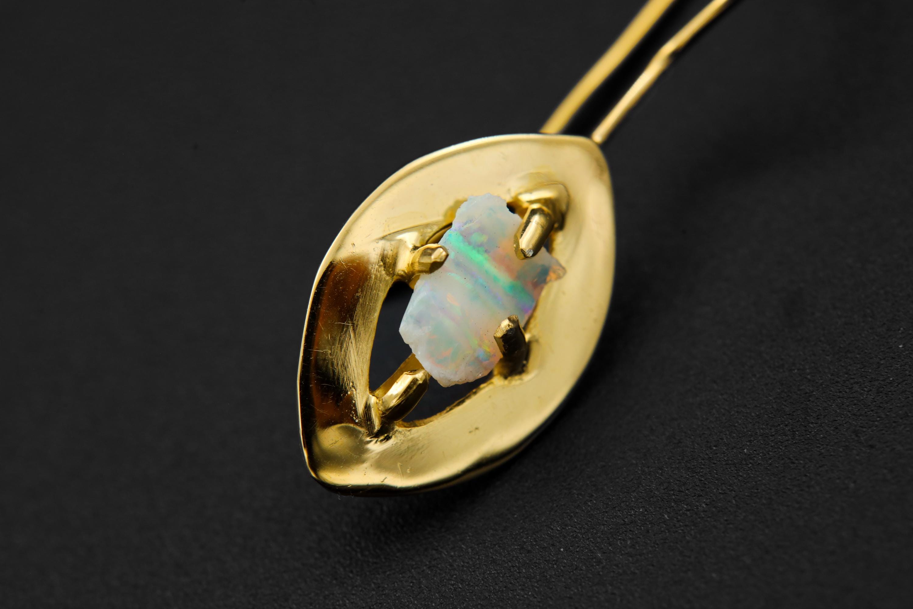 Close-up of White Lightning Ridge Opal earring showing 8-claw gold-plated setting and natural play of colour.