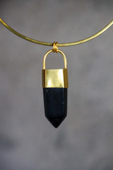 Close-up of dark Smoky Quartz point pendant showing polished crystal facets, gold-plated cap, and strong black-gold contrast.