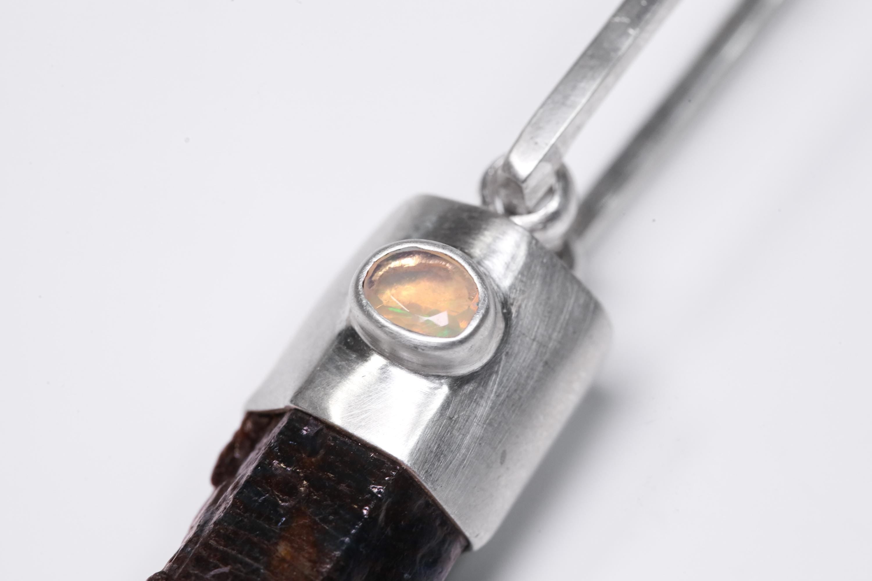 Close-up of Ethiopian Opal accent set in sterling silver above a Blue Apatite crystal point pendant.