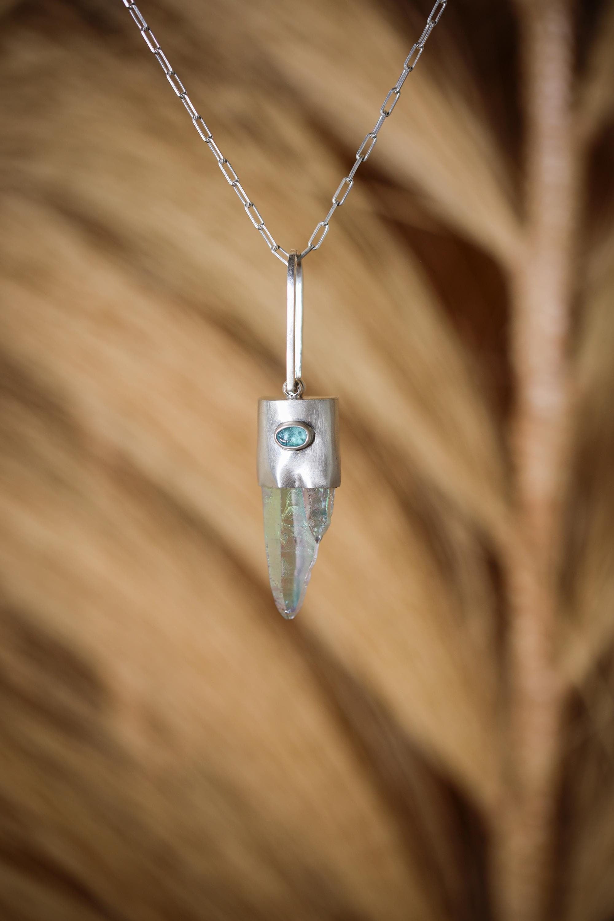 Lemurian Angel Aura Quartz Apatite pendant shown hanging against natural grass texture, with silver chain and blue Apatite accent.